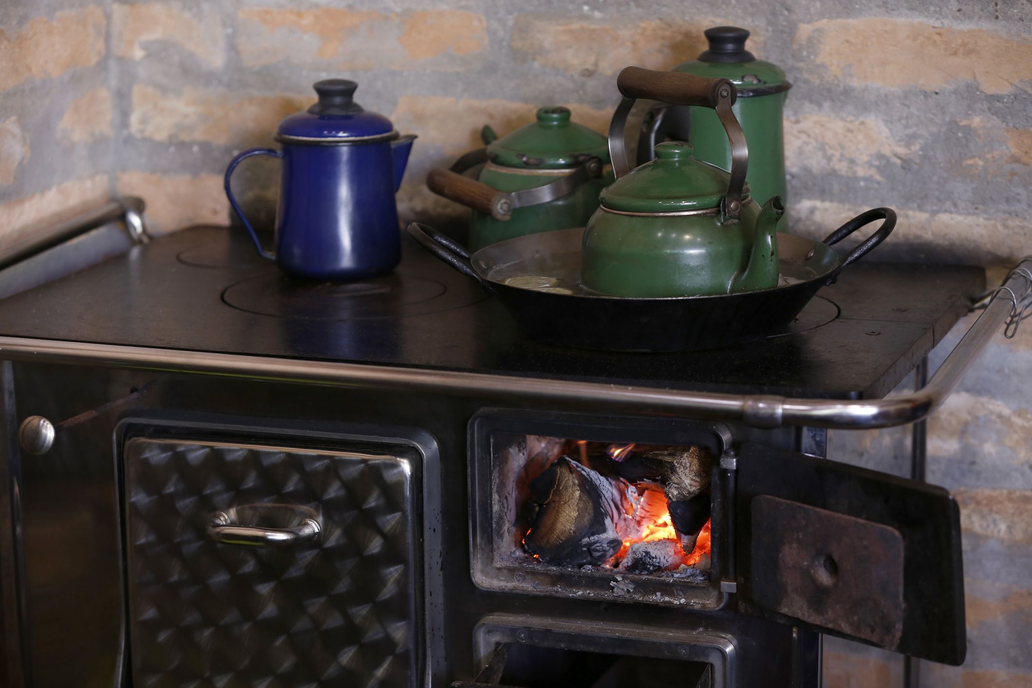 warm fire heating a coffee kettle in wood burning stove. Traditional style in countryside of Brazil