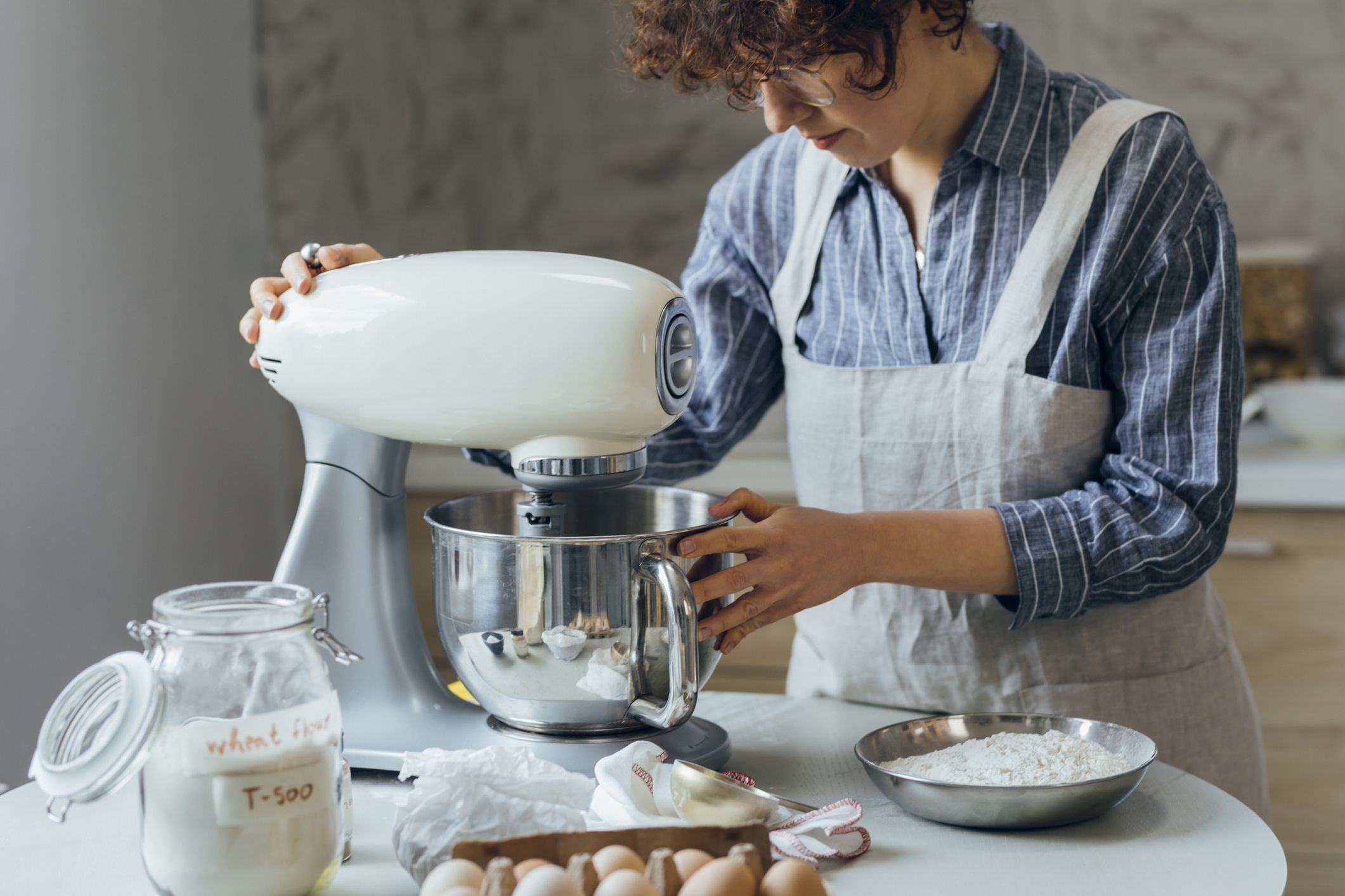 Woman in an apron mixing cookie dough in the kitchen.