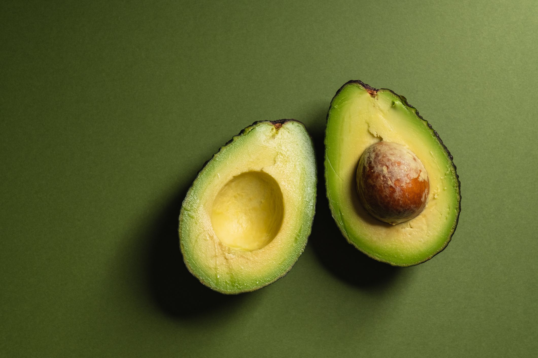 Avocado halves on green background.