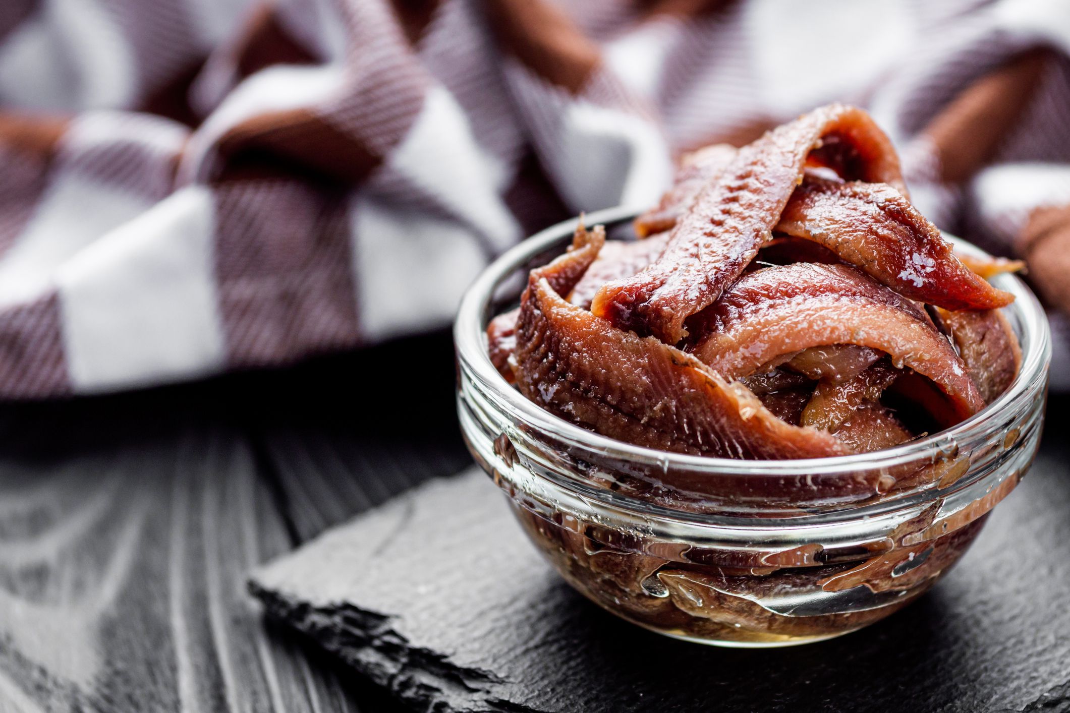 canned anchovy fillet on a black wooden rustic background.
