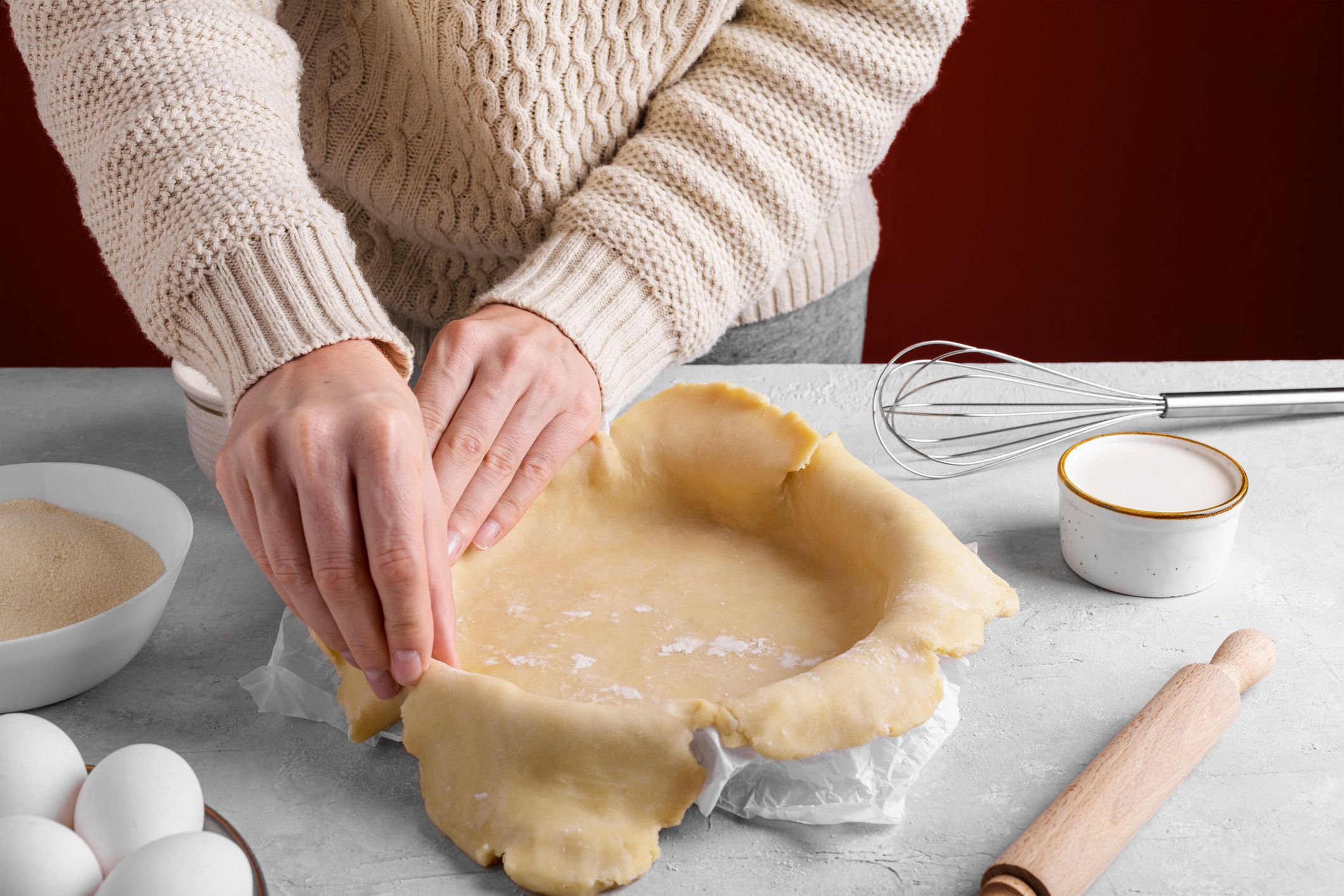 Woman arranging the dough in the pie pan on the table in the kitchen, female hands are putting homemade crust pie dough into a baking dish. Making a base for a shortcrust pie, apple pie, quiche