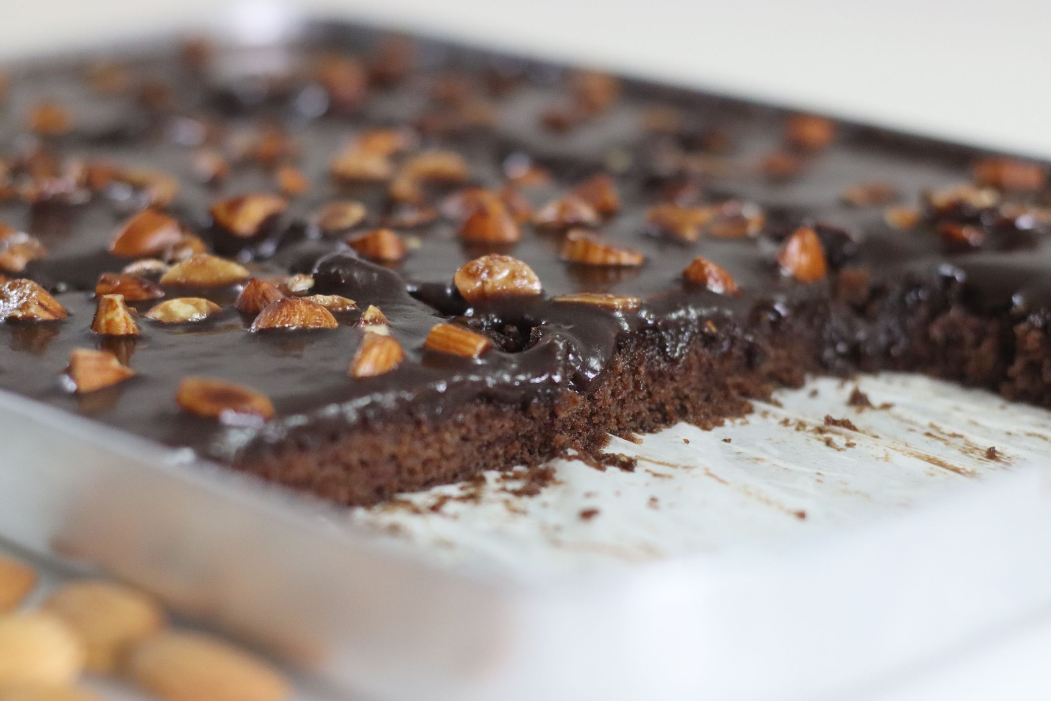 Slicing of Texas sheet cake. Buttery and chocolaty cake sliced to rectangular pieces inside the baking bin. Fresh from Oven. Shot on white background