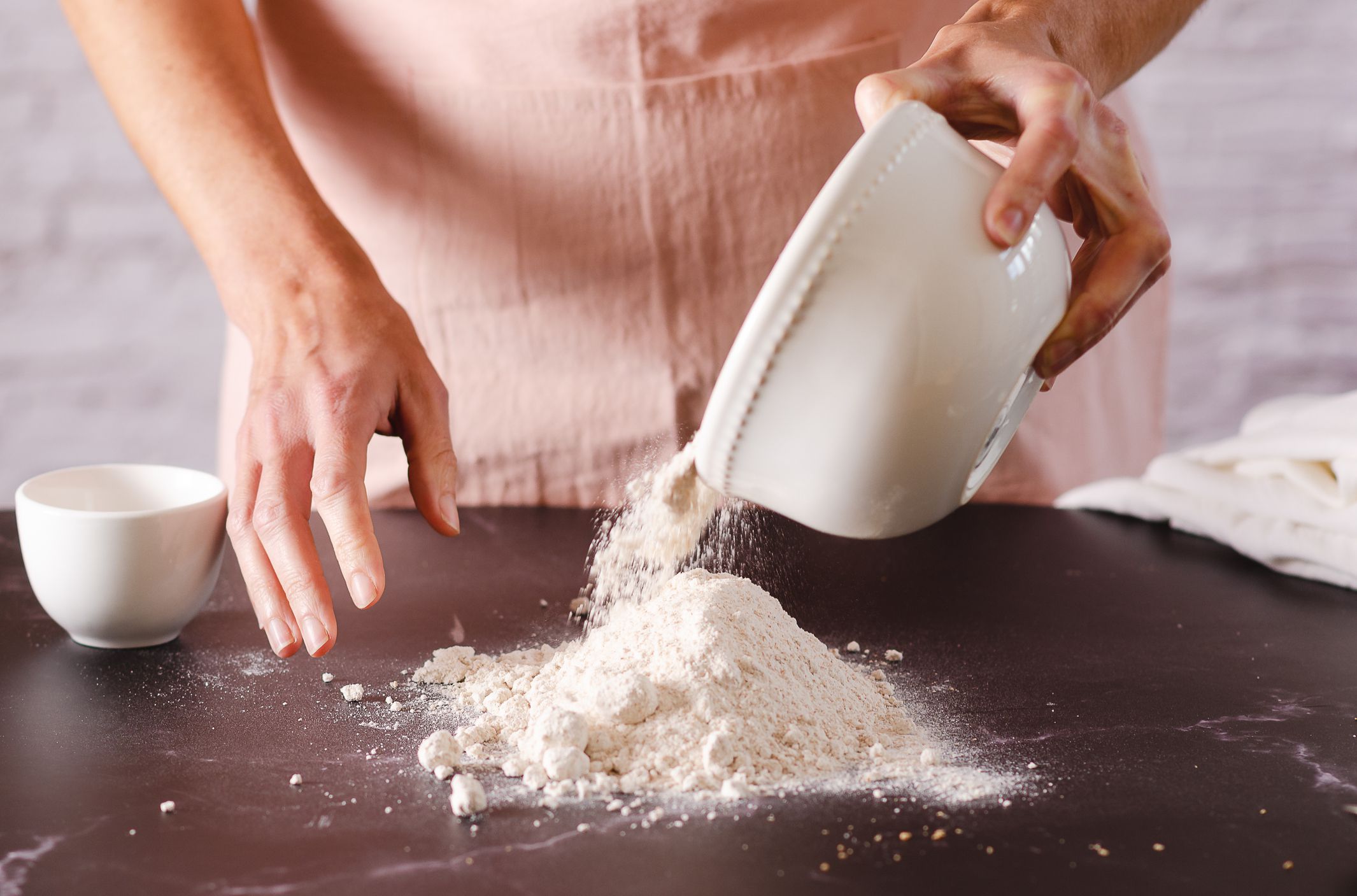 Woman sprinkling flour on a table in the kitchen. Cooking process.