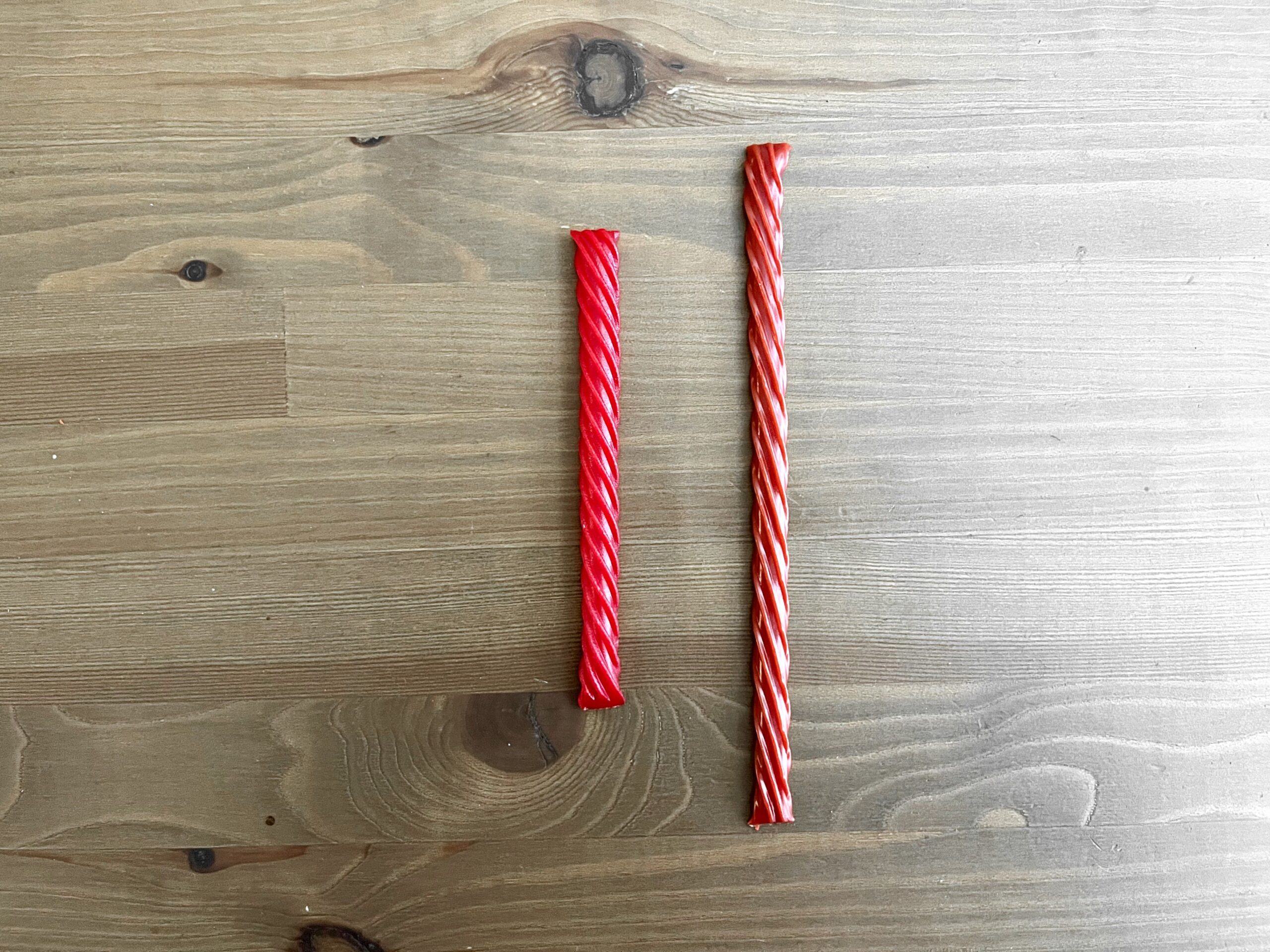 one twizzler and one red vine next to each other