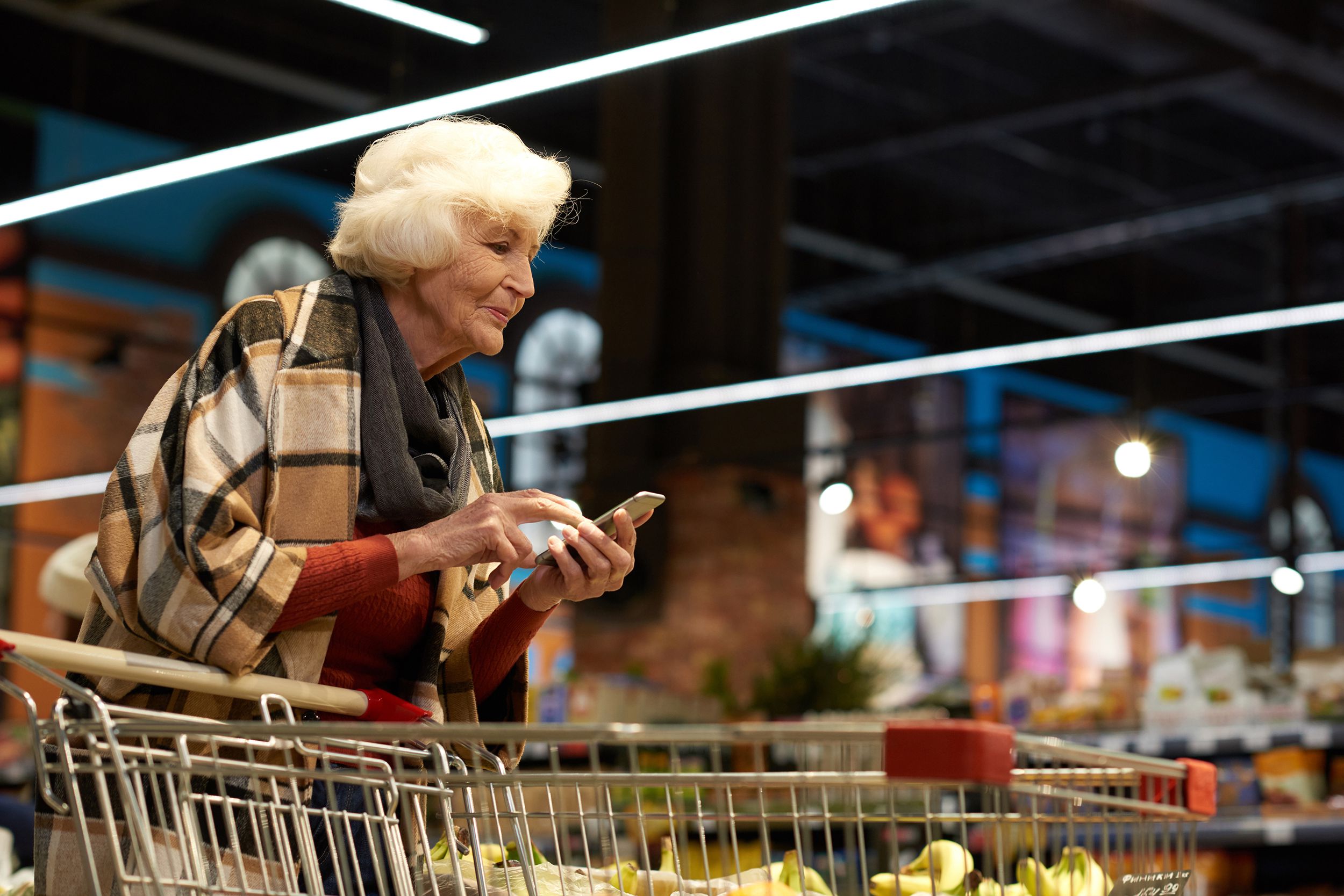 senior woman using smartphone in supermarket