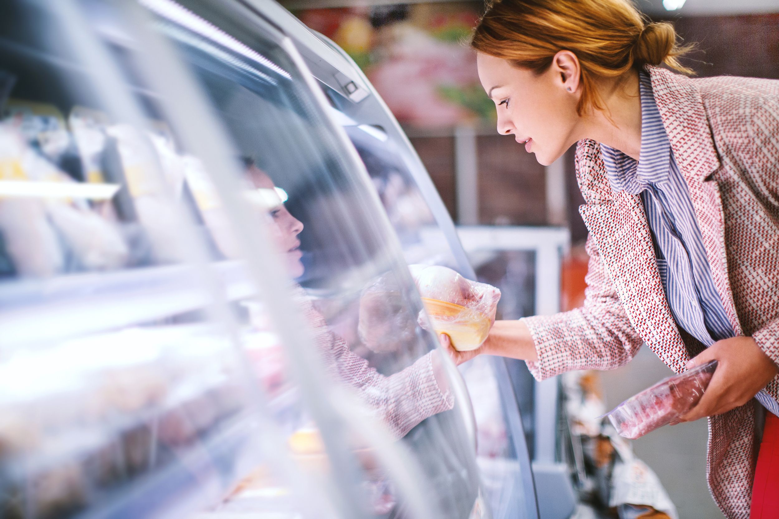 woman buying whole chicken at grocery store