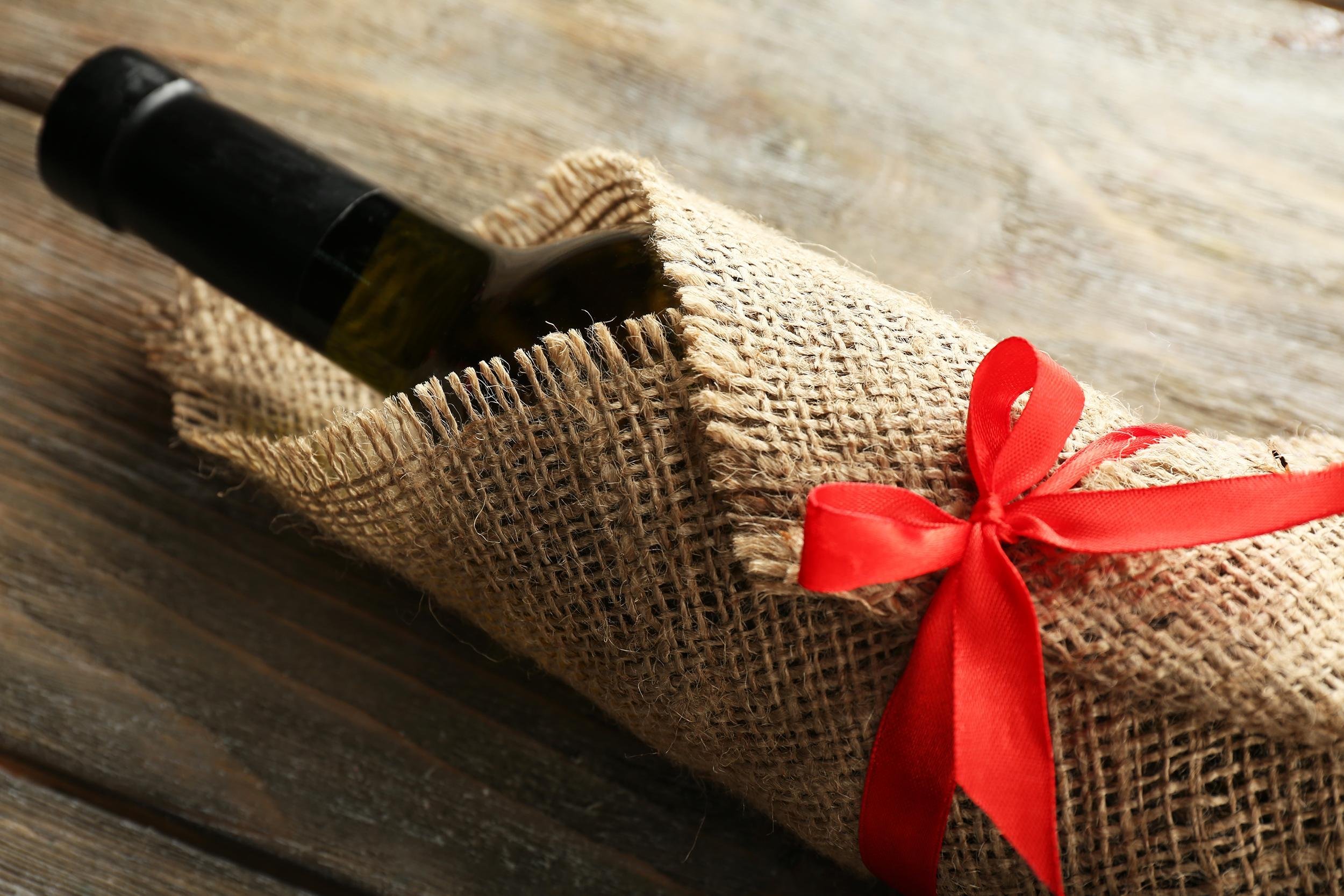 wine bottle wrapped in burlap cloth on wooden planks