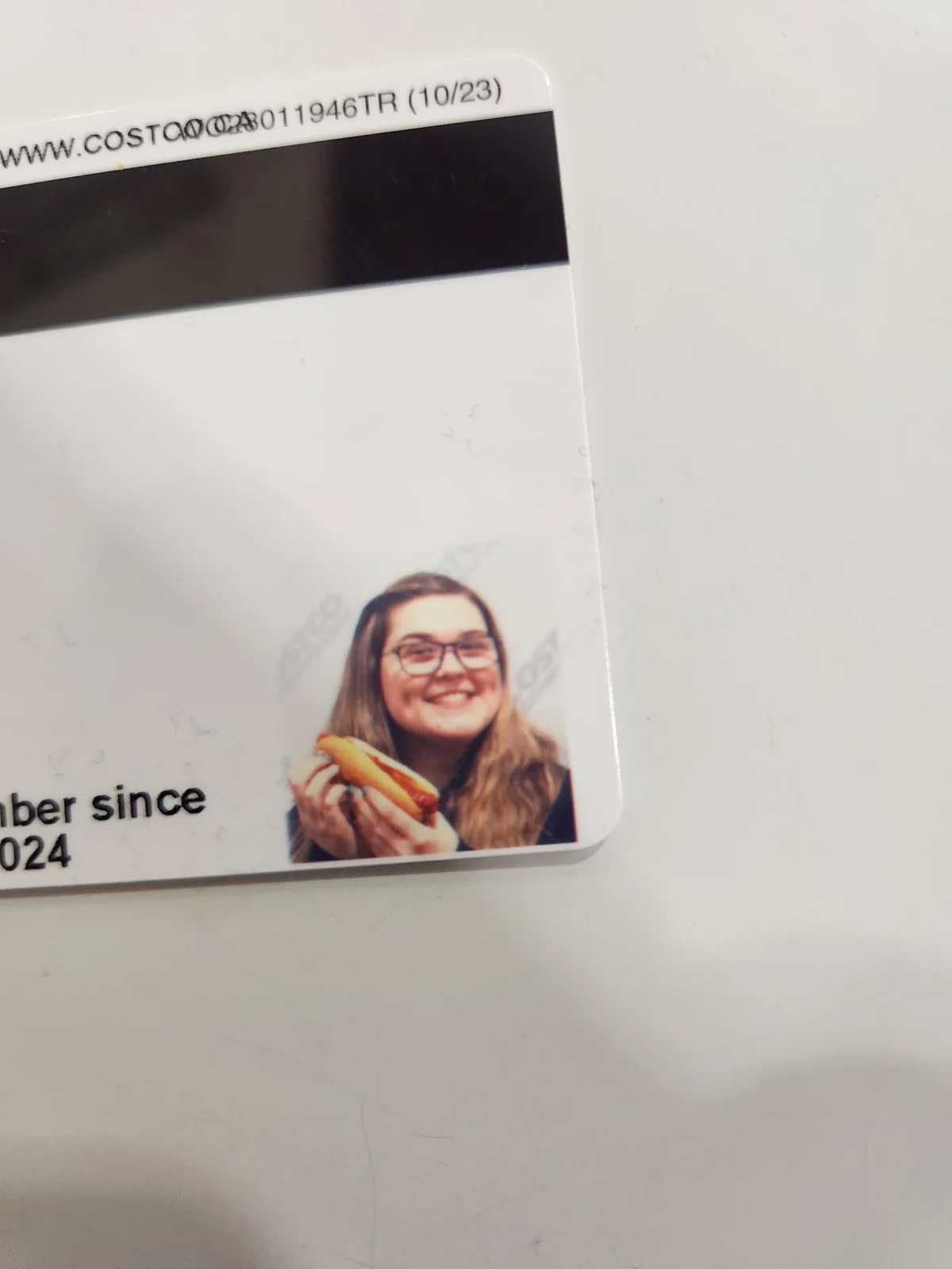 Woman holding a hot dog in her Costco membership card photo