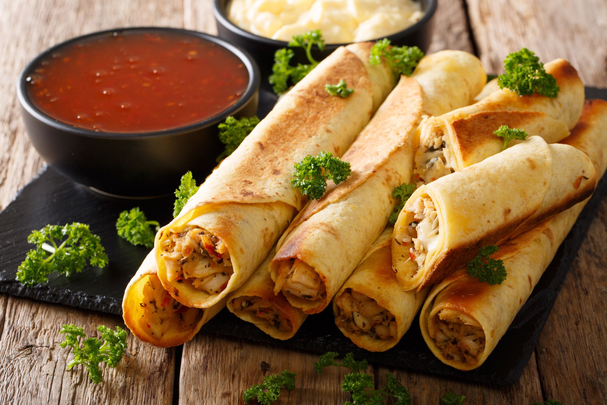 Tasty taquitos with chicken and two sauces close-up on the table. horizontal