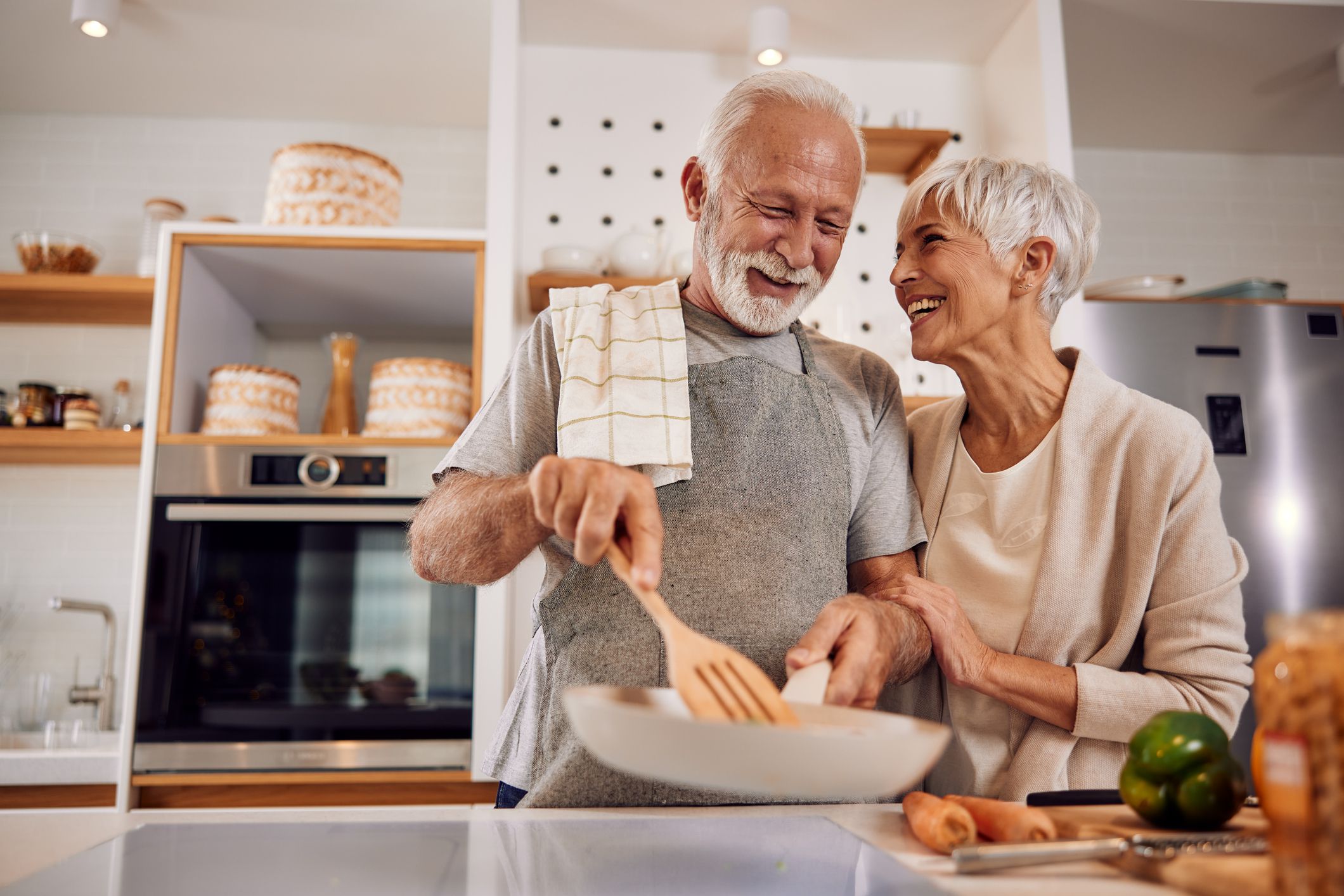 An older couple cooking a healthy vegan meal with vegetables together