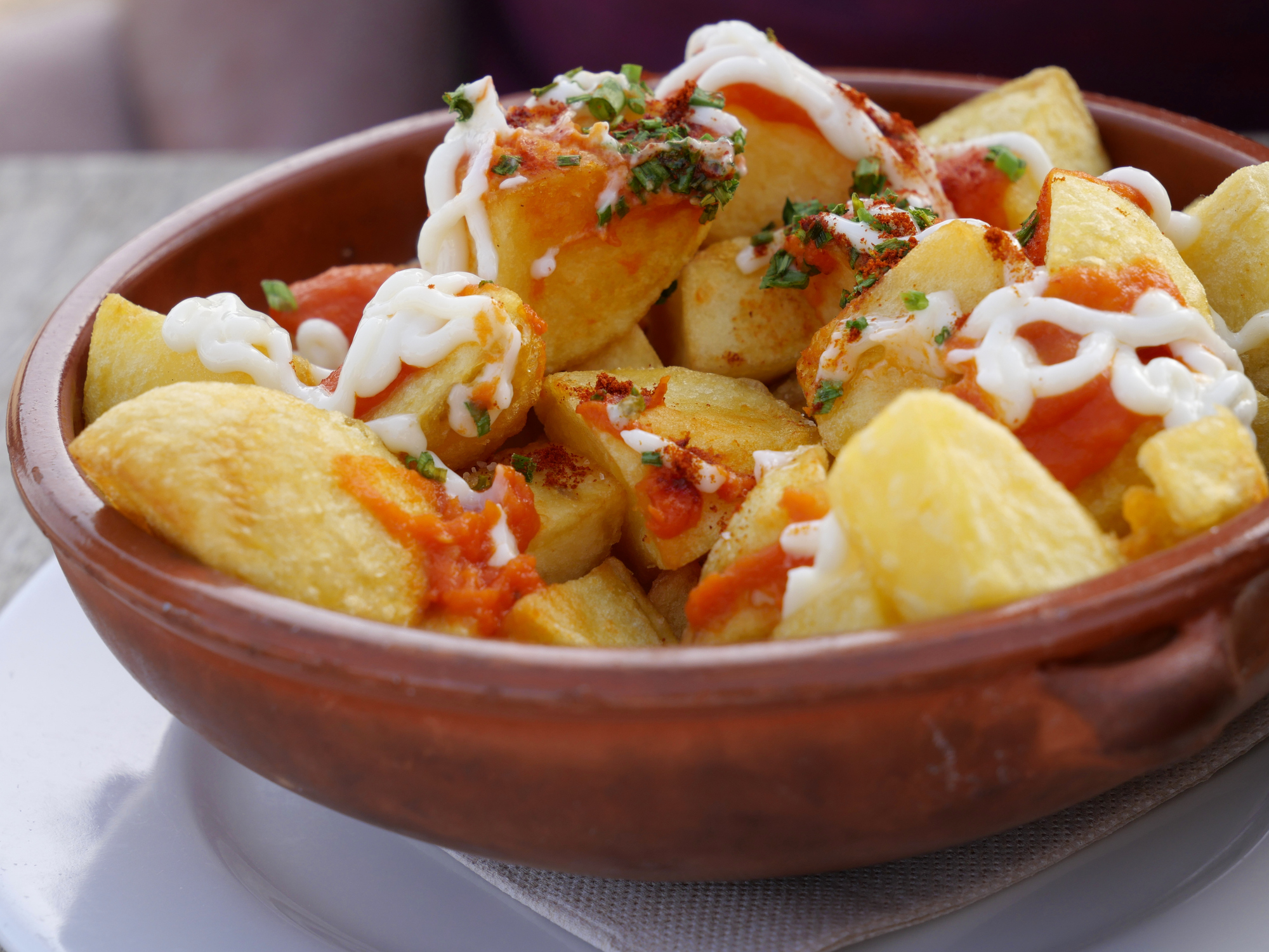 Closeup of Patatas Bravas in a Brown Ceramic Bowl