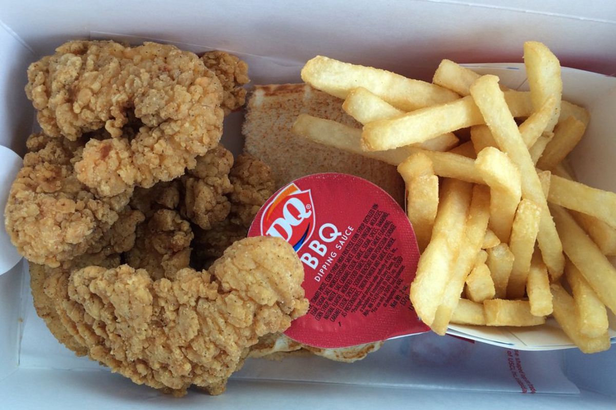 Closeup of Dairy Queen Chicken Finger Value Meal with fries and a cup of BBQ dipping sauce in a serving box