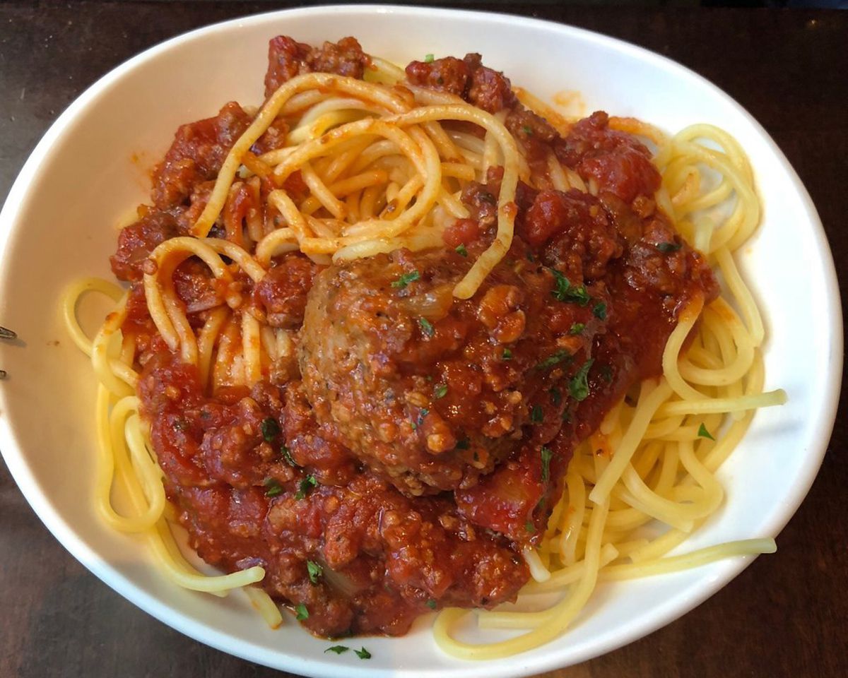 Closeup of Olive Garden Spaghetti and Meatballs in a white bowl on a wooden table at Olive Garden