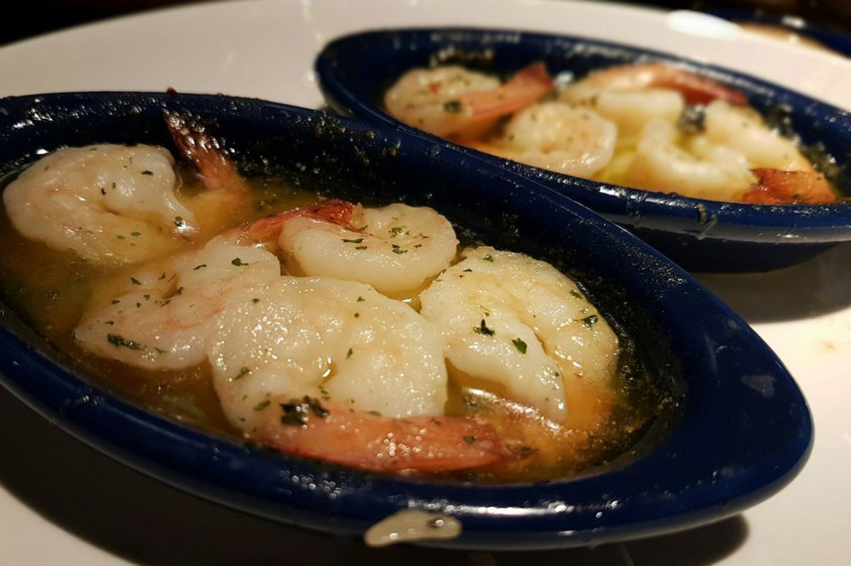 Closeup of Red Lobster Garlic Shrimp Scampi, two servings in black serving trays, selective focus, on a white serving plate