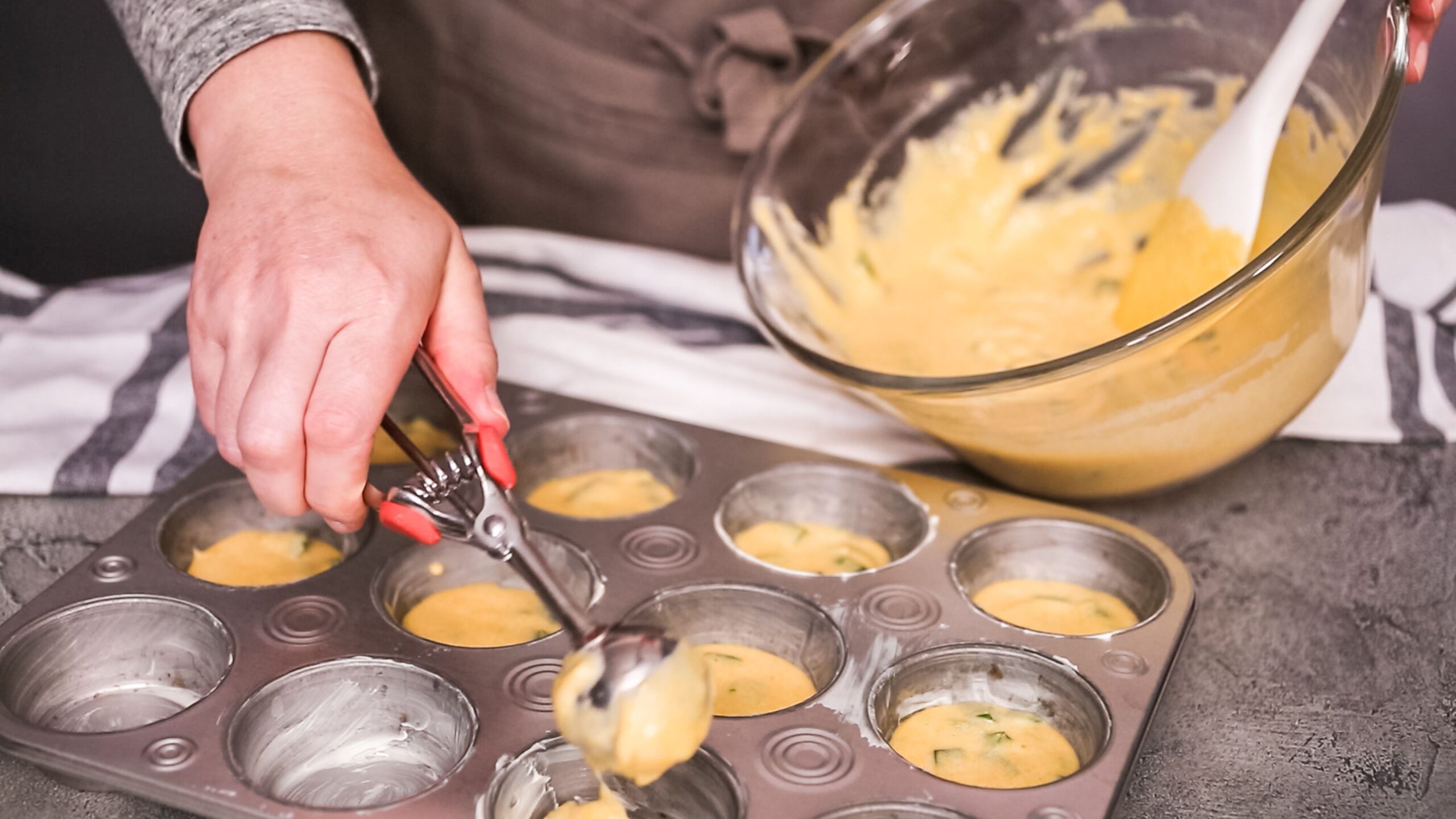 Step by step. Filling metal muffin pan with cornbread batter to bake spicy jalapeno cornbread muffins.