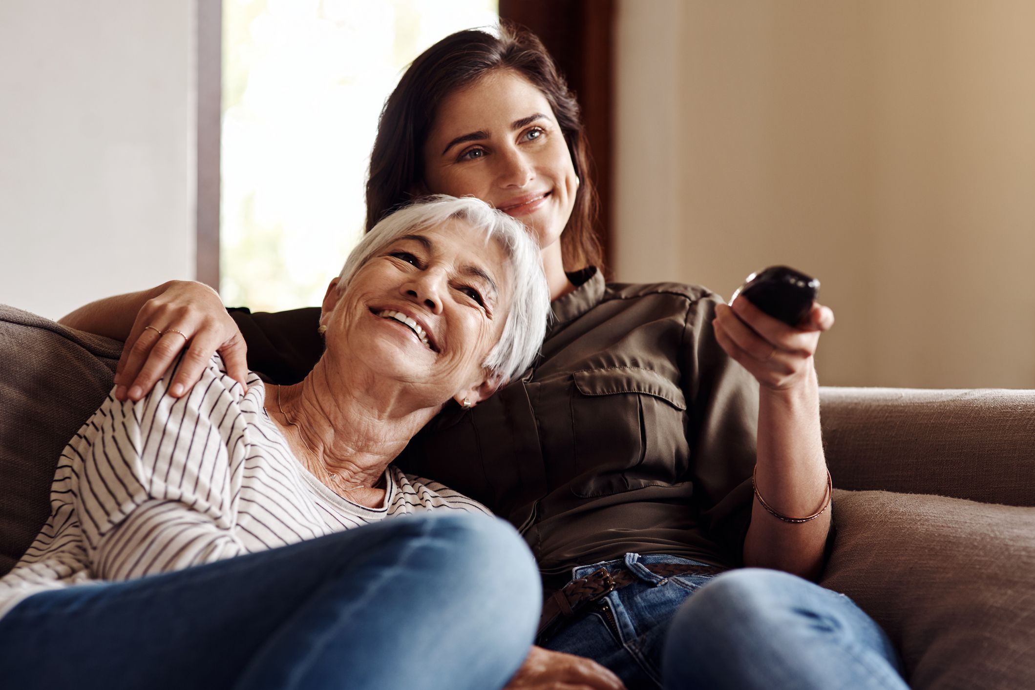 Shot of a young woman watching tv with her elderly mother at home
