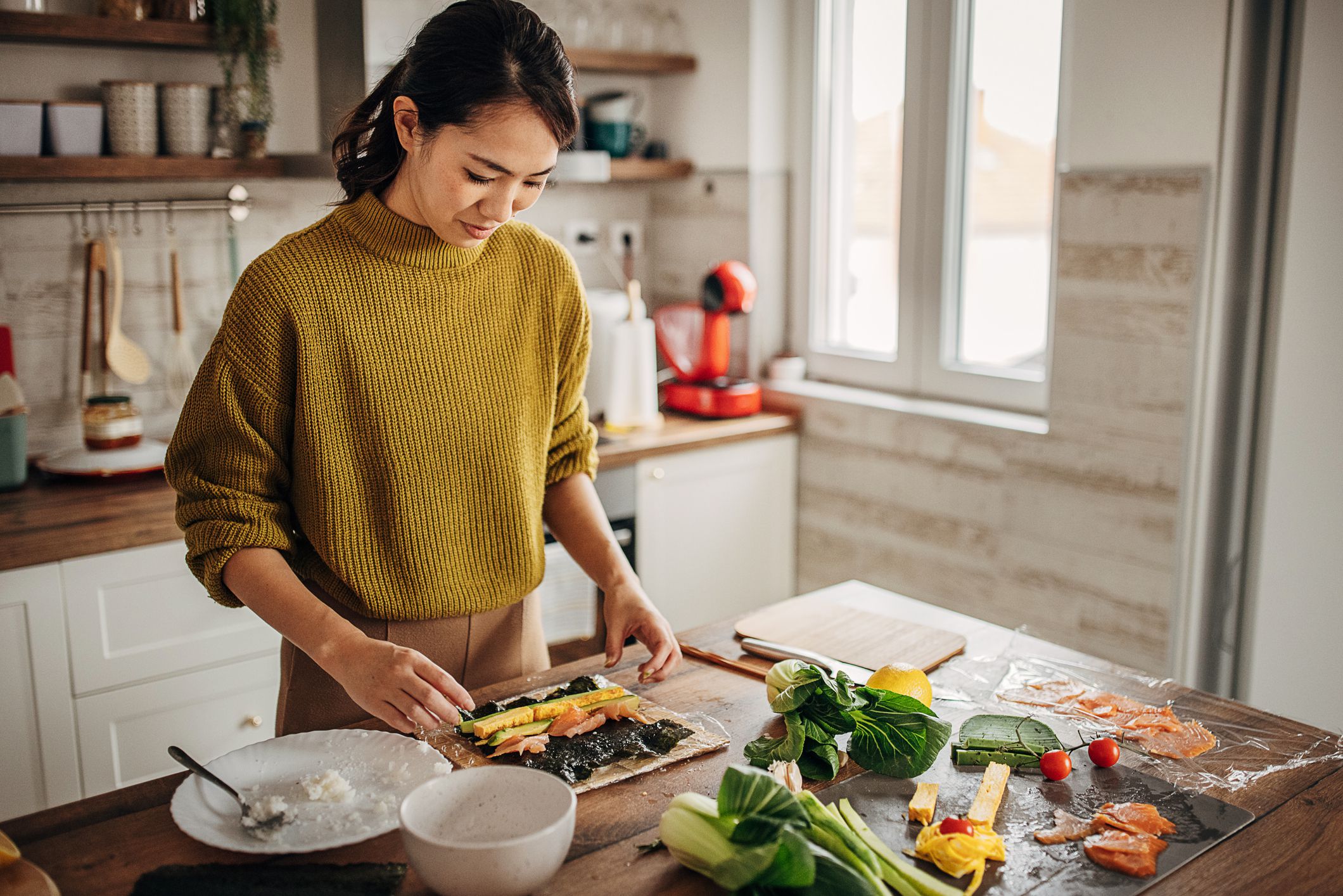 One woman, modern Japanese female preparing sushi in kitchen at home.