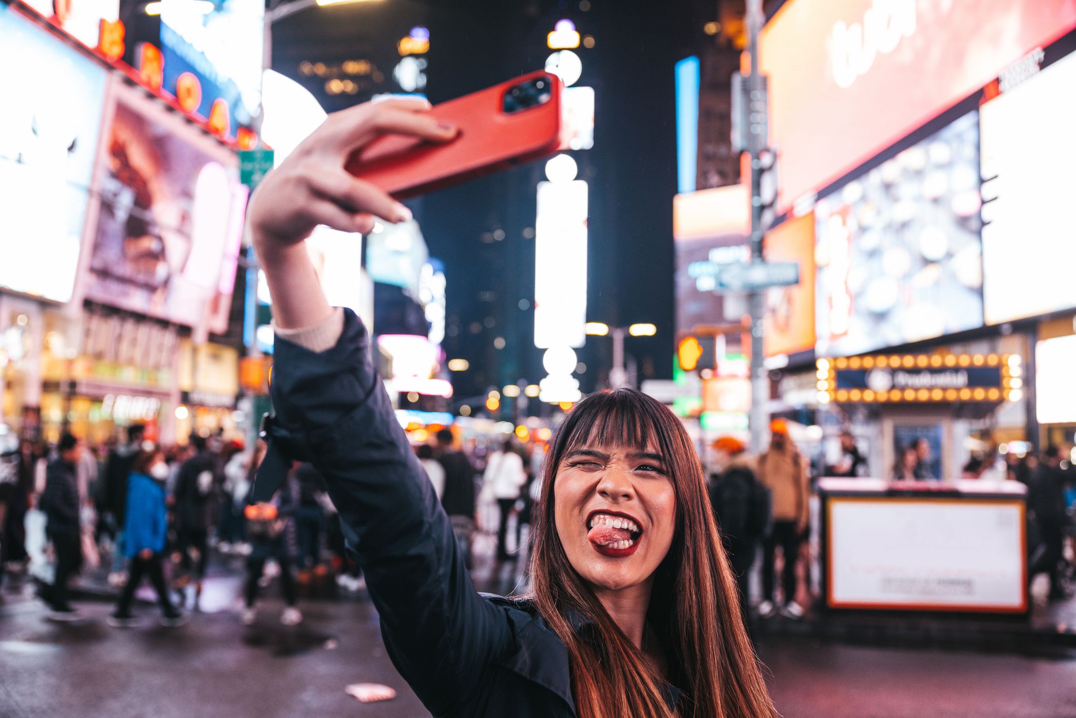 Midtown New York, young Taiwanese tourist woman spending a night in Times Square and sharing on social media with her smart phone.