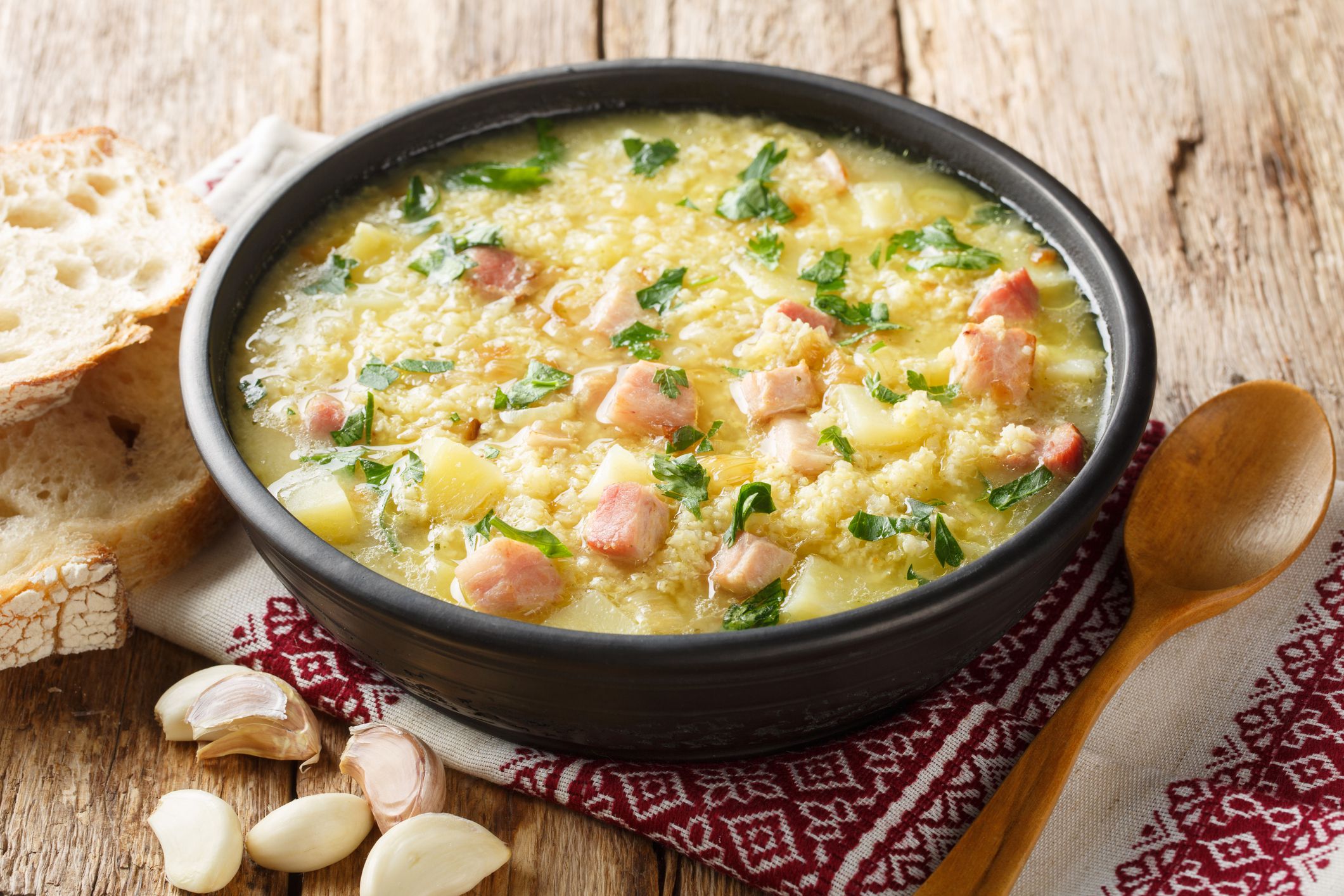 Cossack Ukrainian rich soup kulish made of millet, potatoes, onions with bacon close-up in a plate on the table. horizontal