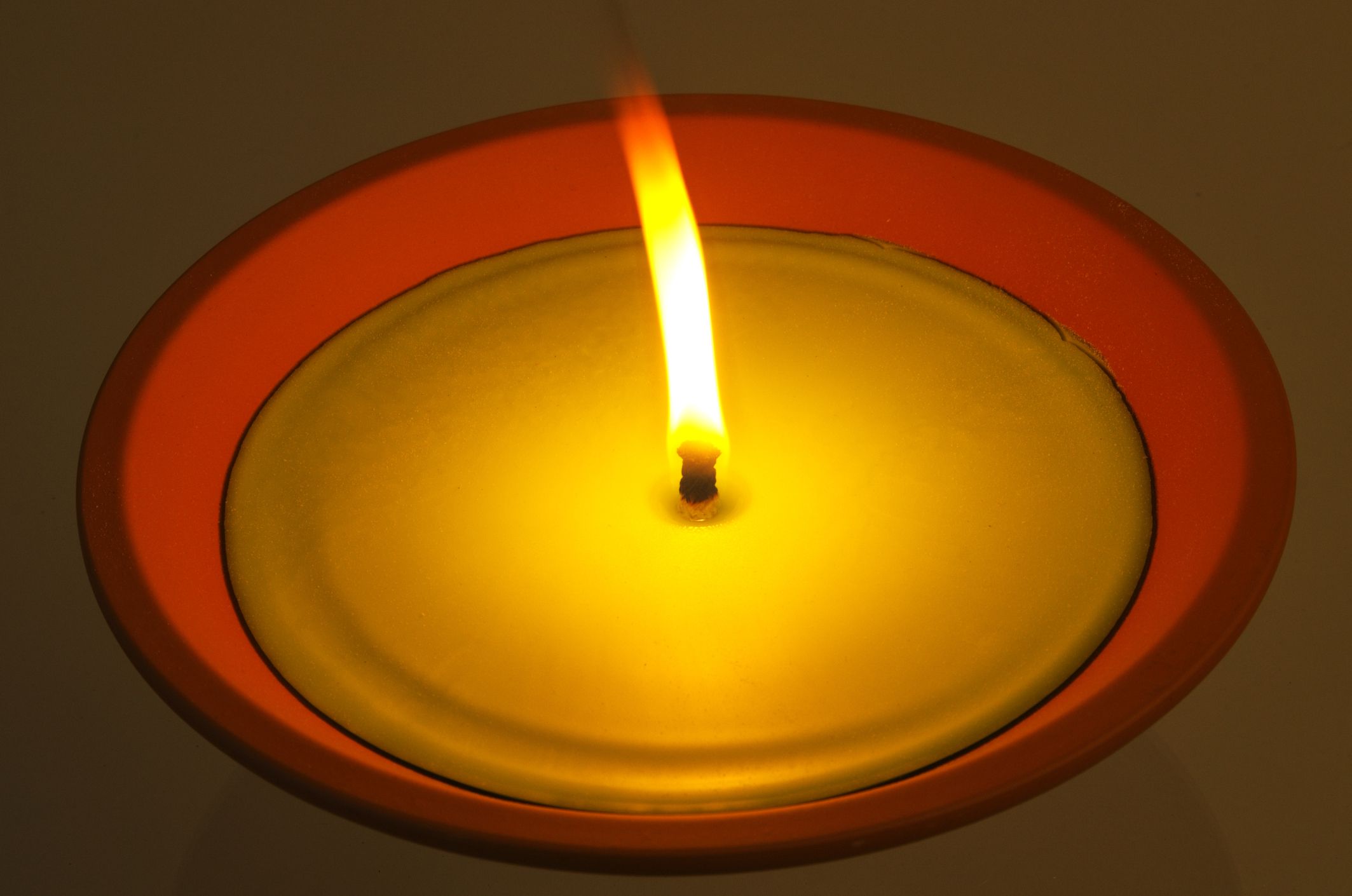 Citronella candle in terracotta pot for outside use, lit in the dark.