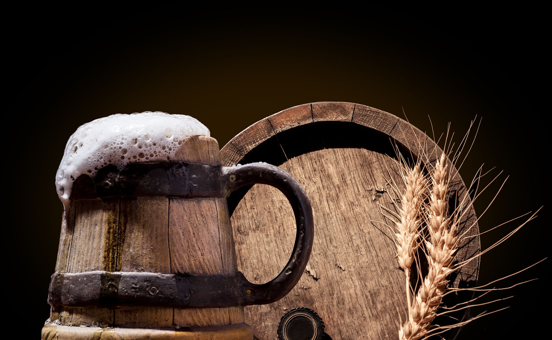 Ancient wooden pint with beer in front of oak barrel with wheat ears. Beer Fest set.