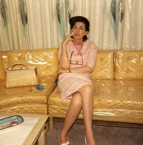 woman sitting on a couch covered in plastic smoking a cigarette in the 1970s
