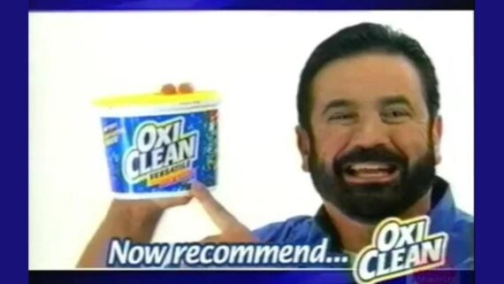 A smiling man with a beard holds a tub of OxiClean Versatile Stain Remover, pointing at it. The text on the image reads, &ldquo;Now recommend&hellip; OxiClean.&rdquo;
