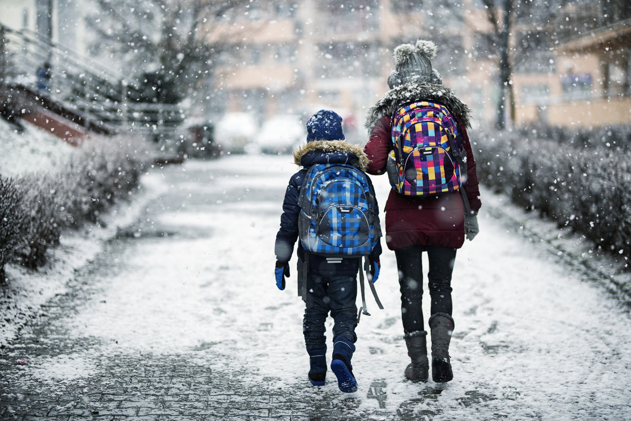 Brother and sister going to school on winter day. Elder sister aged 12 is walking her younger brother aged 8 to school.Nikon D850