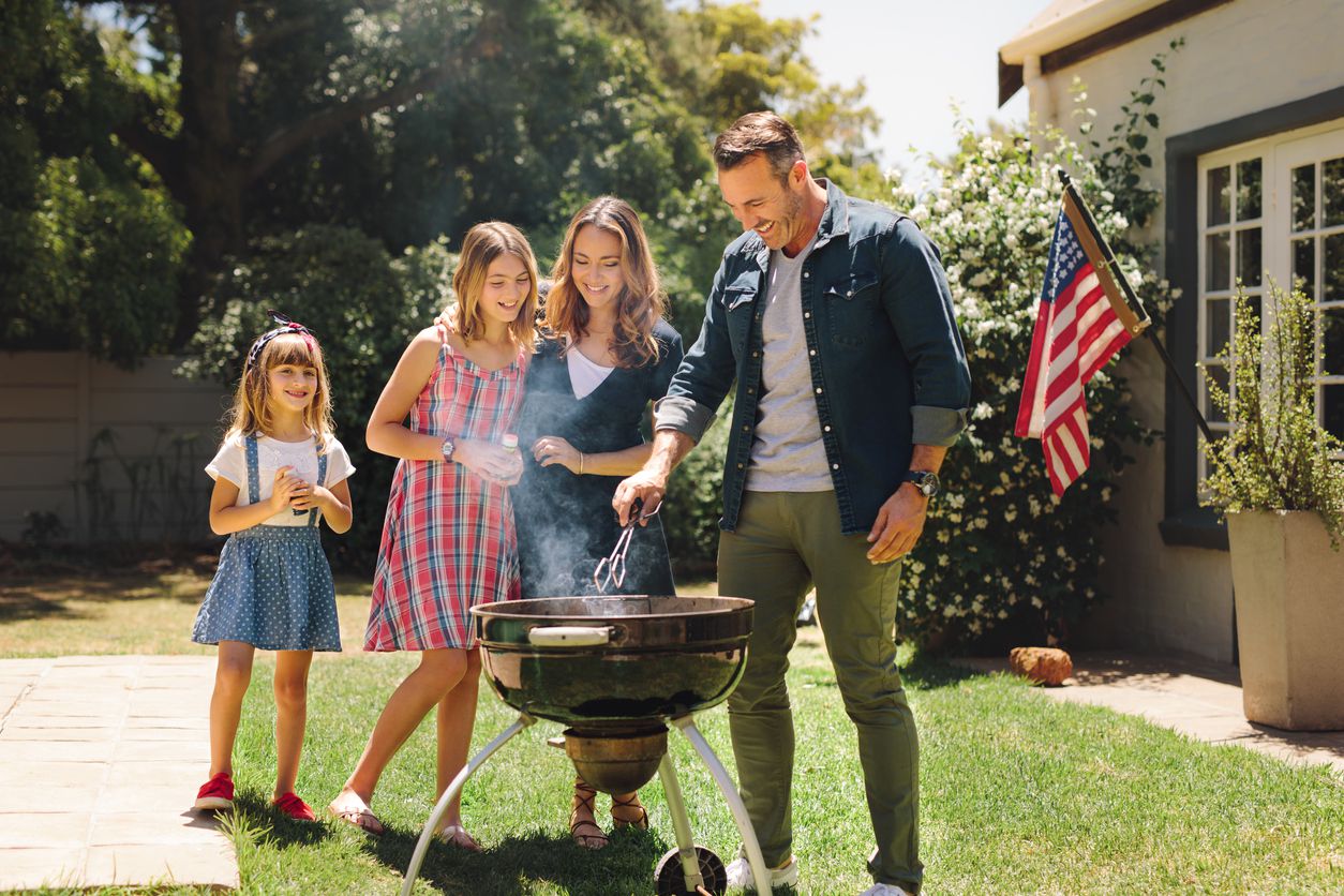 american family of four watching dad grill