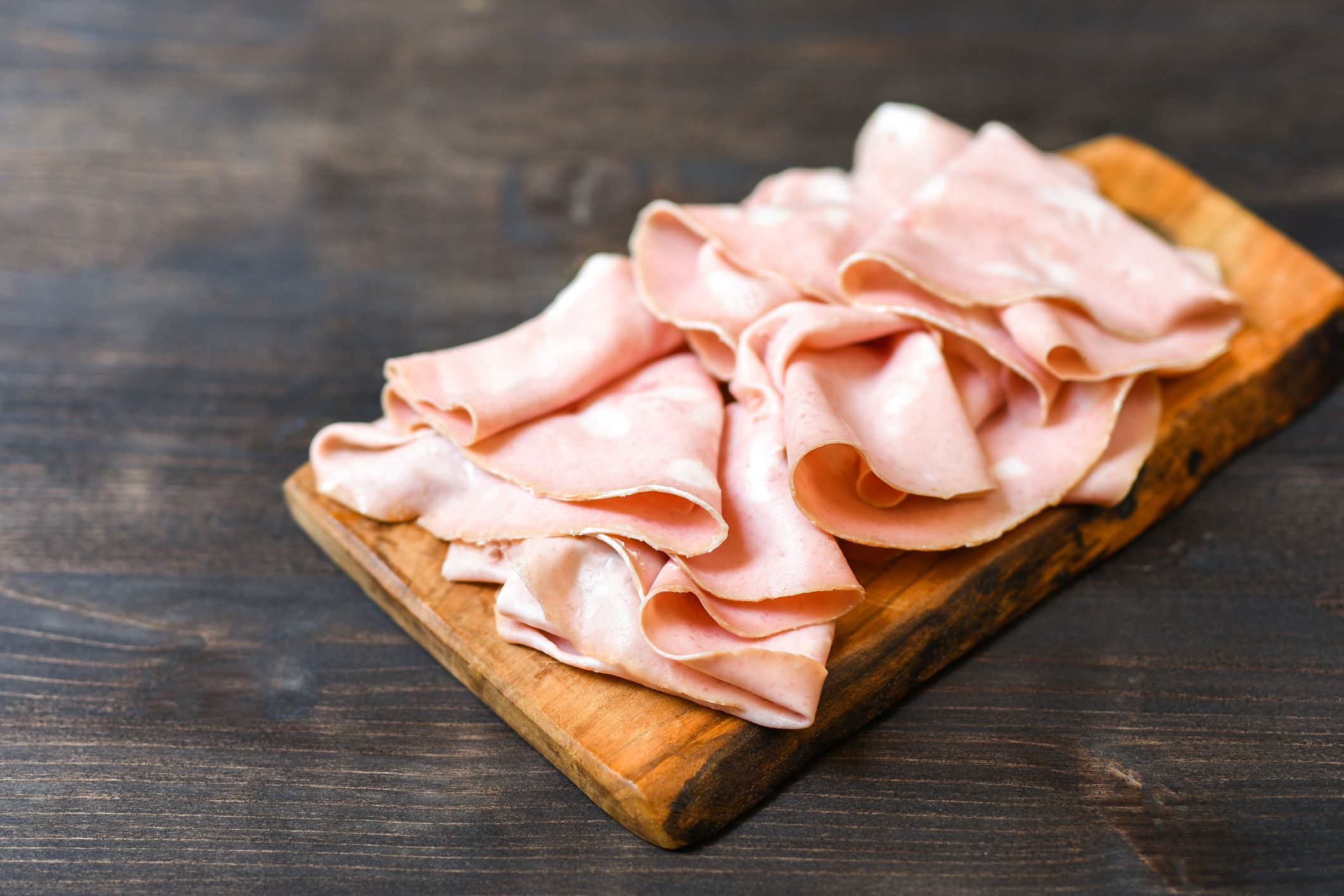 Traditional Italian antipasti mortadella on a wooden plate, served with olives