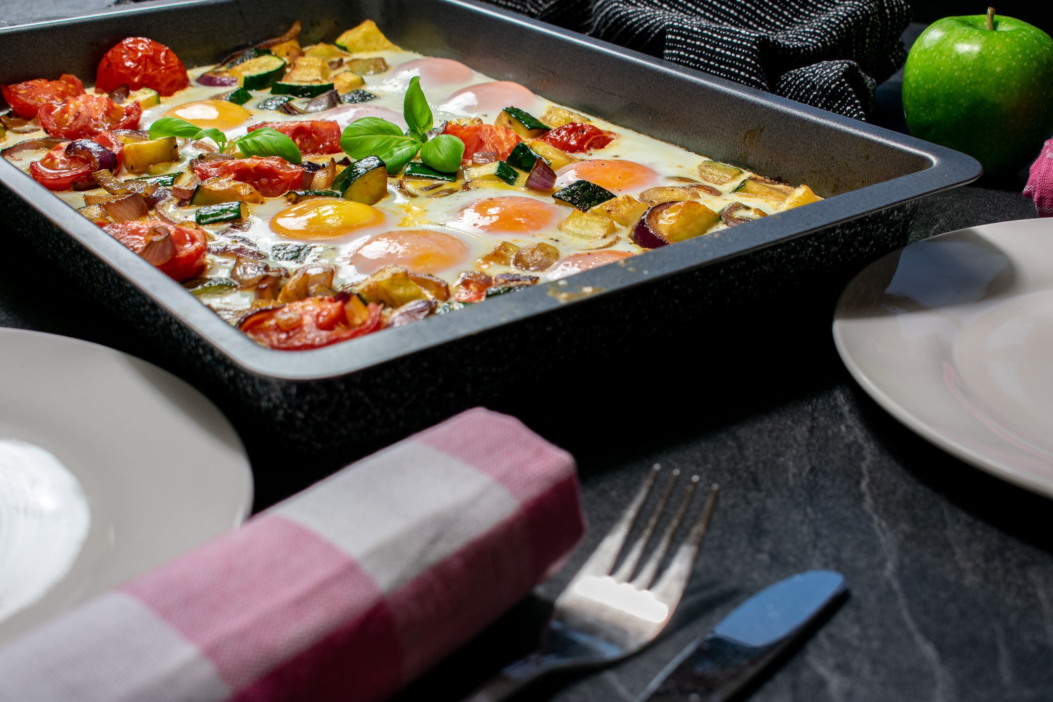oven baked eggs with healthy vegetables served on a baking tray - ready to eat