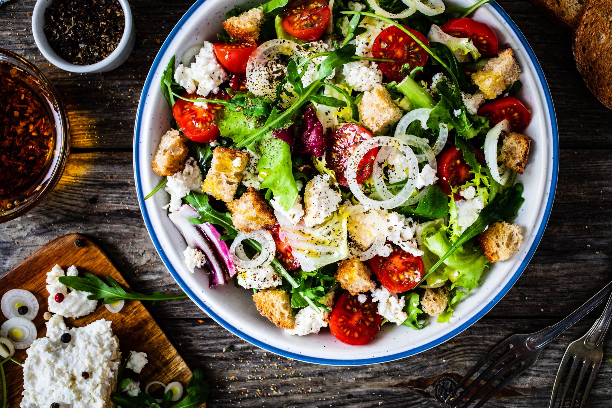Vegetable salad with cottage cheese and toasted bread on wooden board