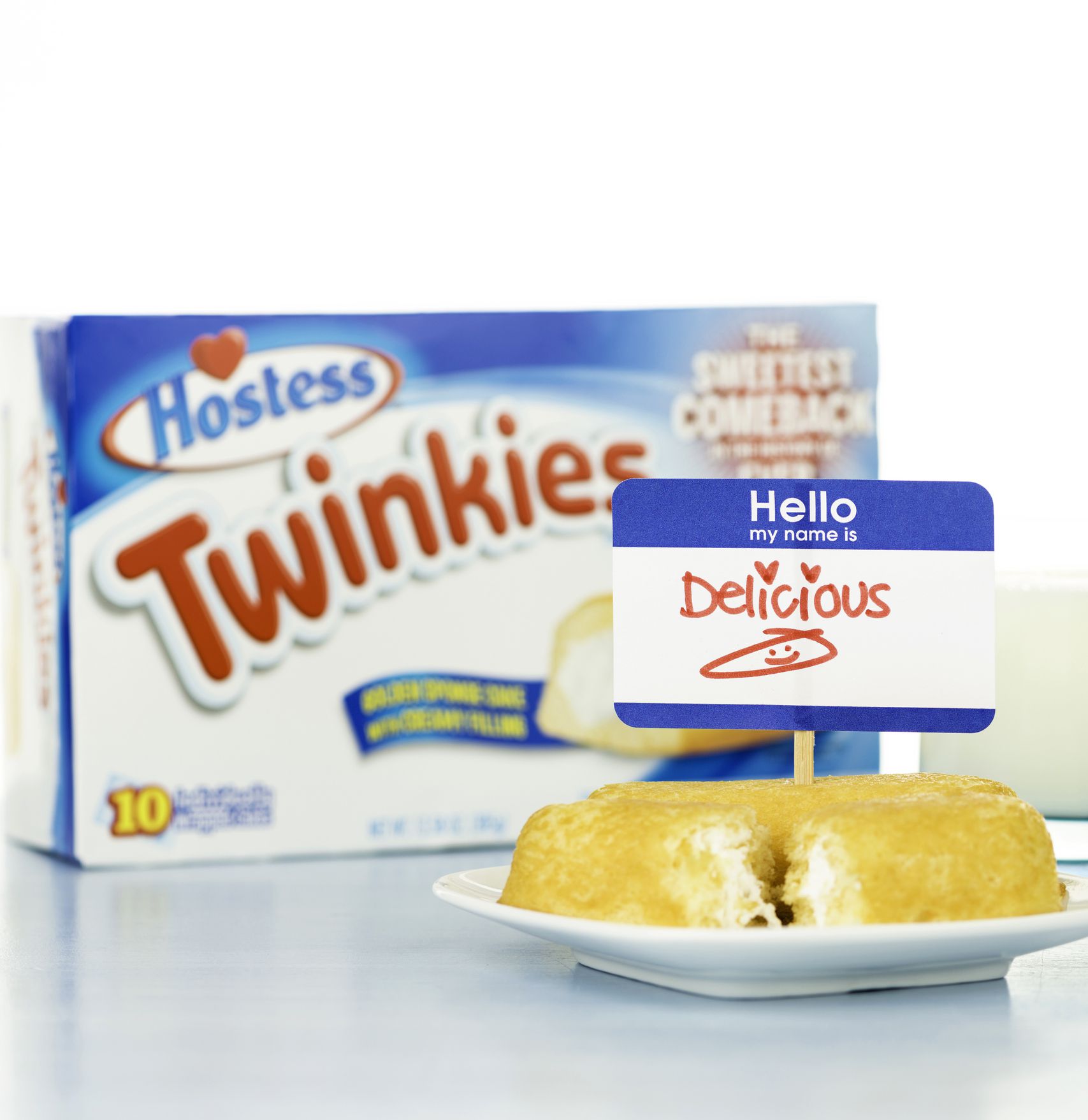 Suffolk, Virginia, USA - September 28, 2013: A horizontal studio shot of two Hostess Twinkies cakes, with a sign reading: Hello my name is Delicious, in front of a defocused box of Hostess Twinkies and a glass of milk.