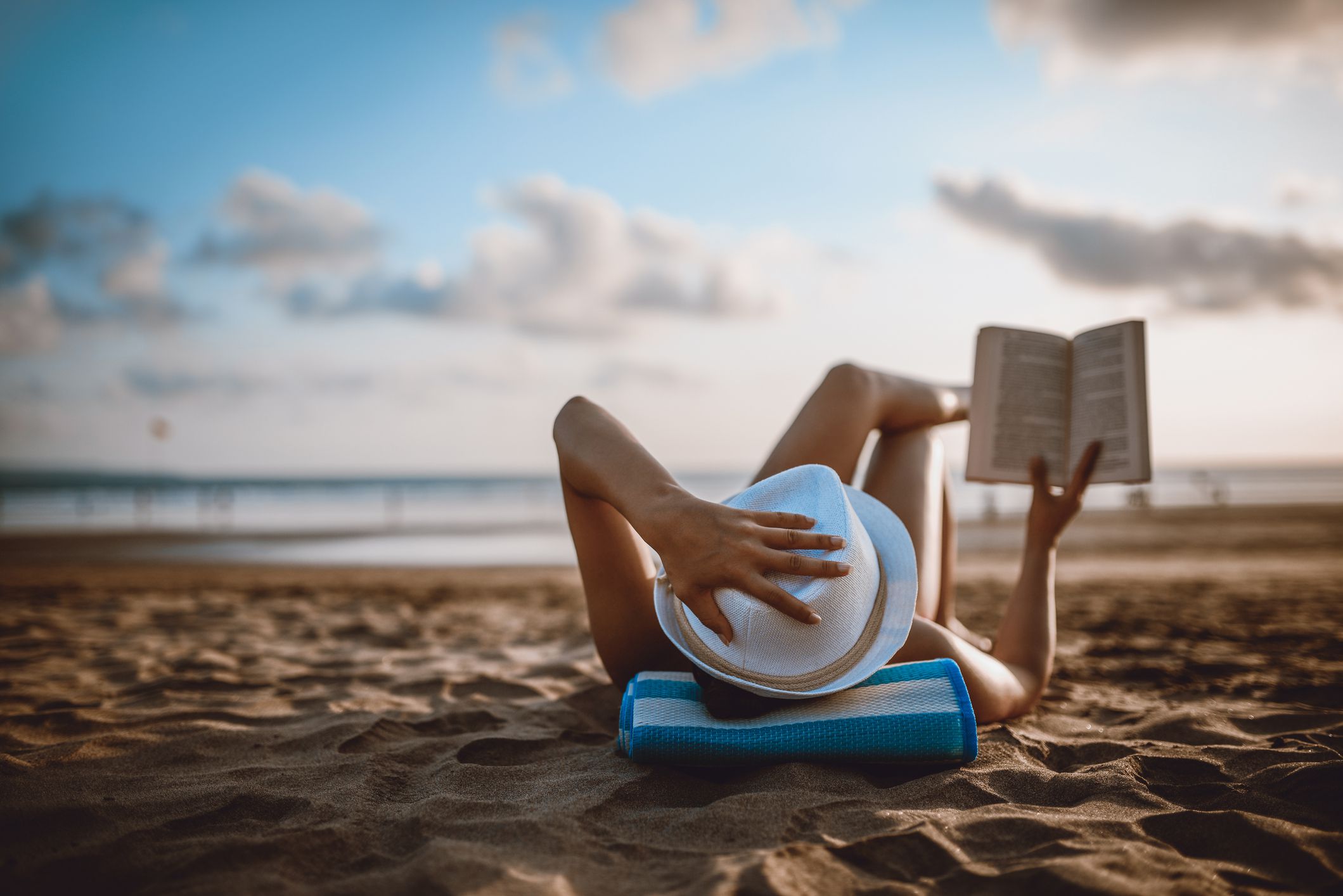 Female Reading and Enjoying Sunset on Beach by the Ocean