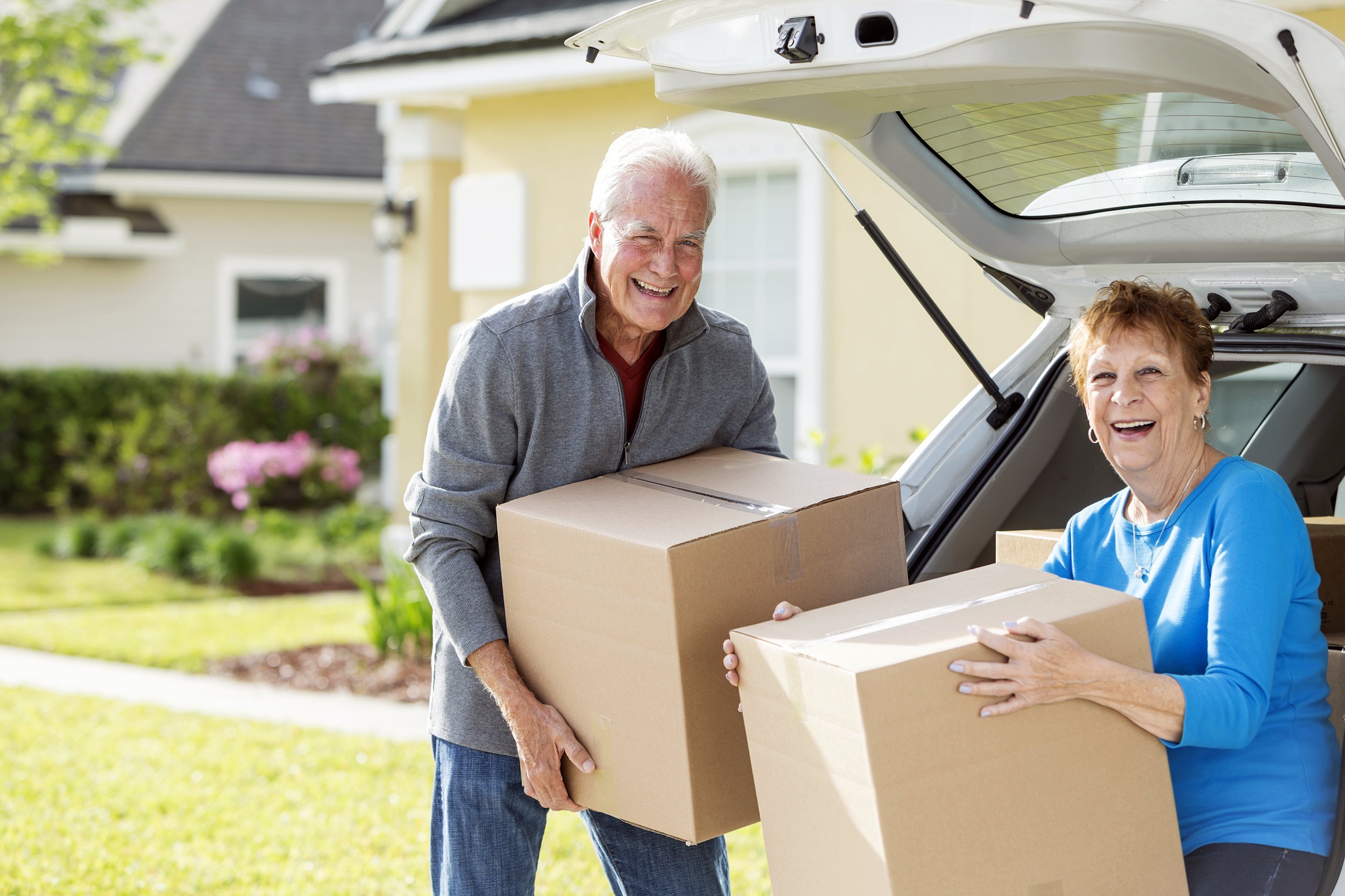 Senior couple moving, putting moving boxes into their car
