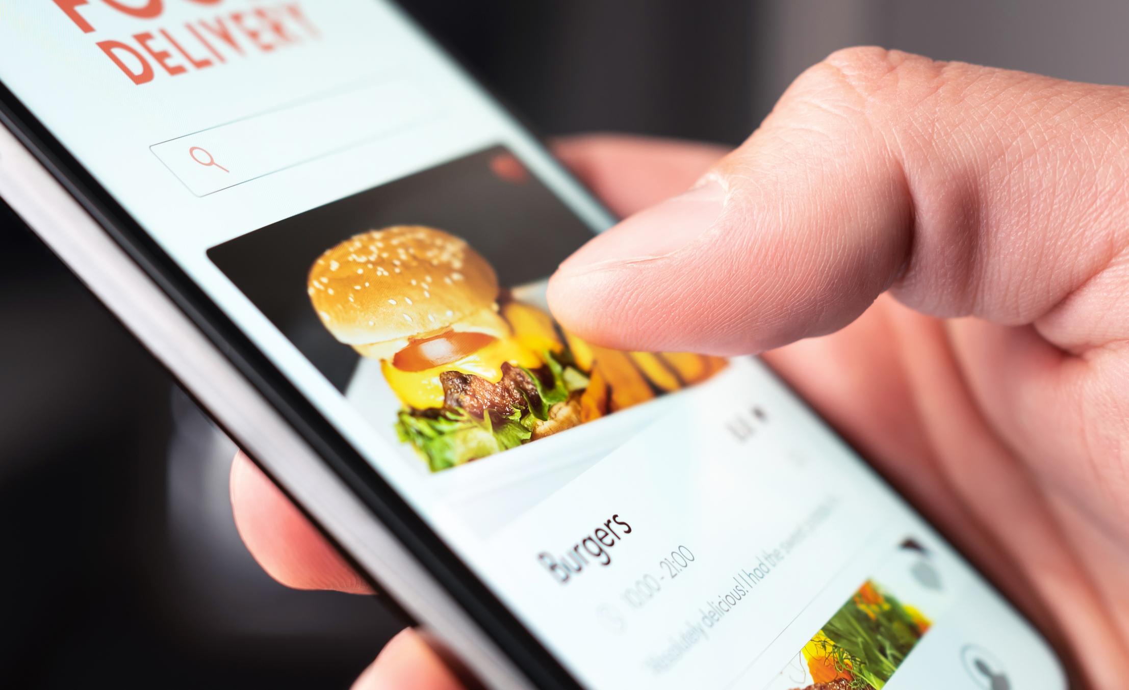 Closeup of Right Hand Holding a Smartphone With a Delivery App Opened With a Hamburger Image