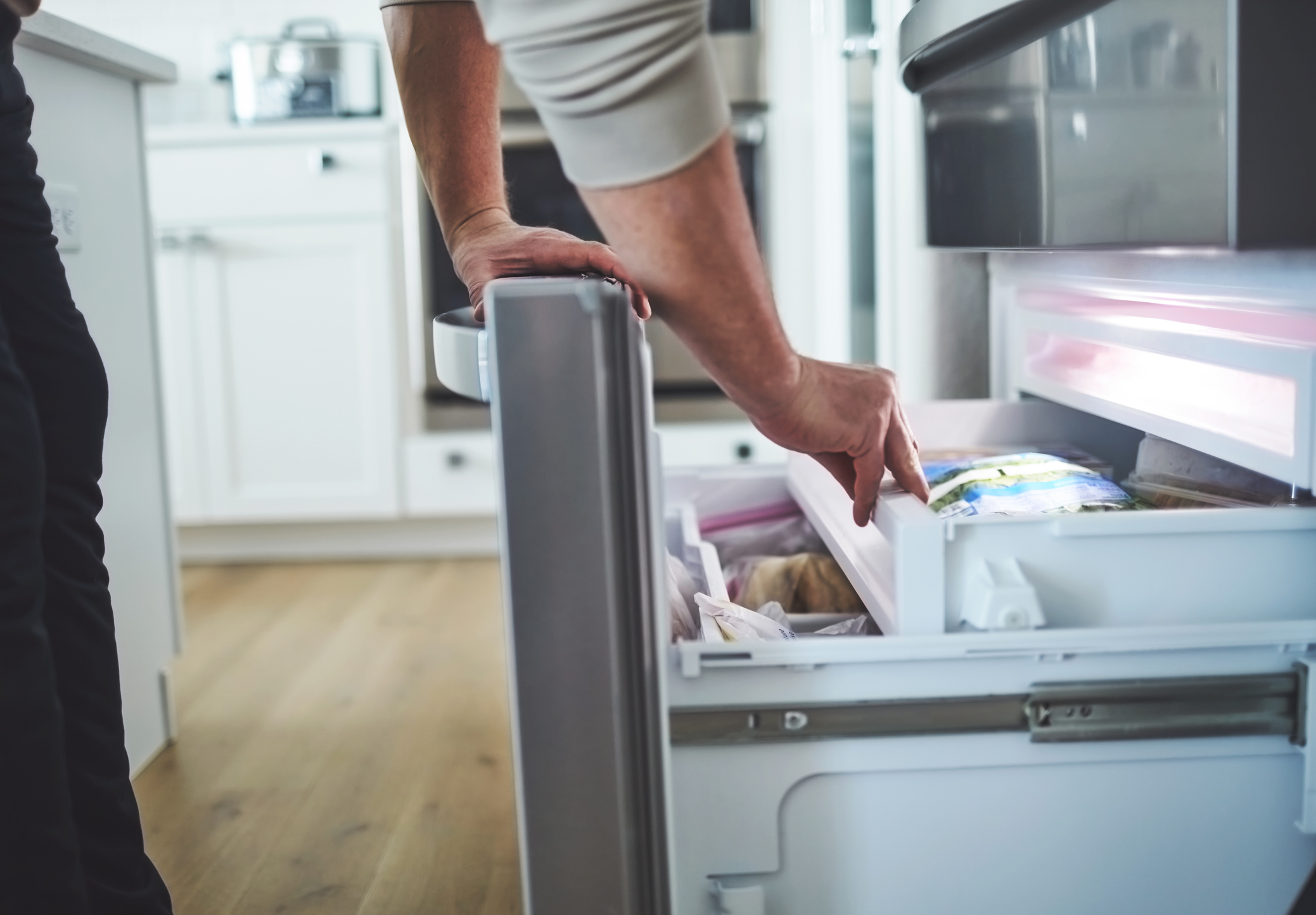 Male Looking in an Opened Freezer Drawer of a Refrigerator