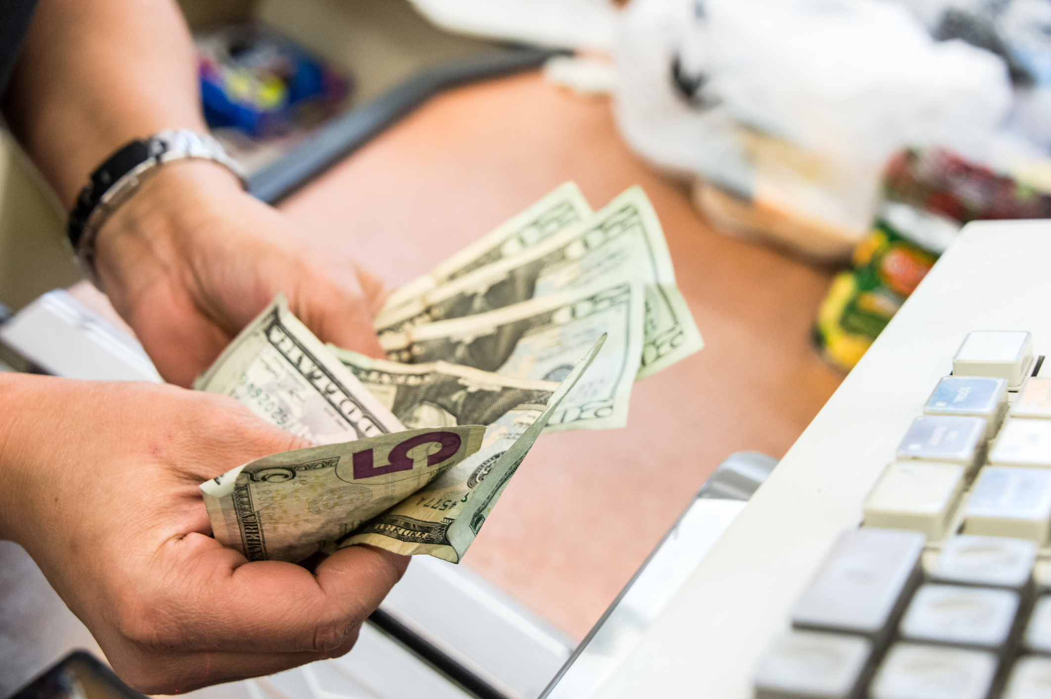 Closeup of Grocery Store Cashier Hands Counting Cash for Customer