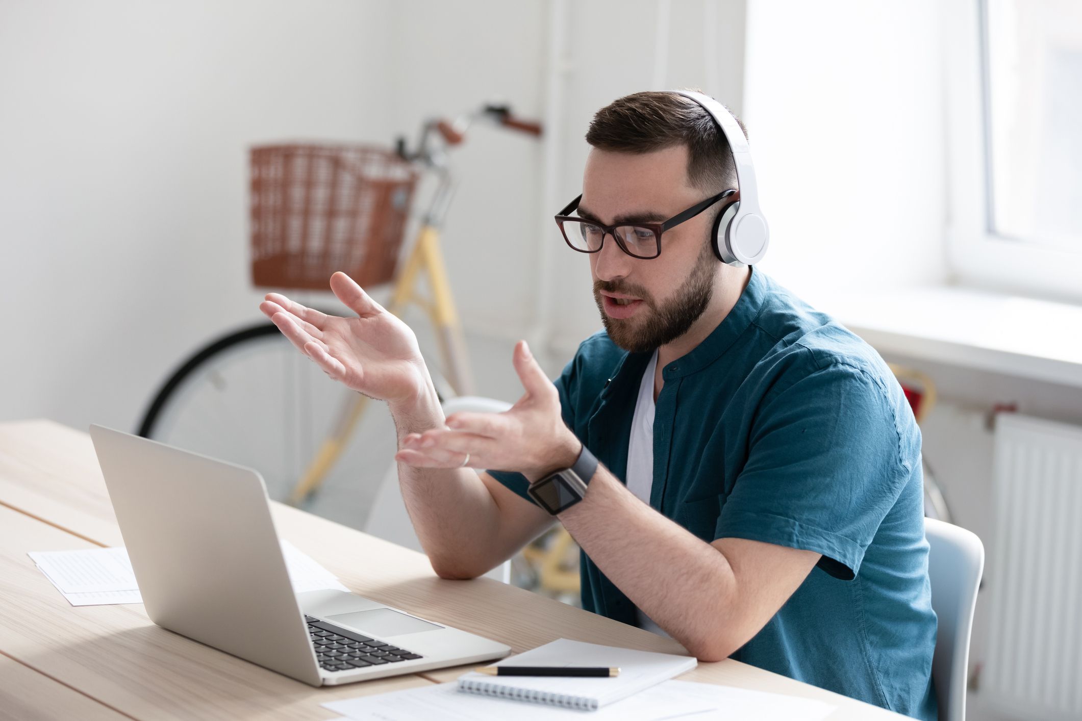 young man wearing headset looking at laptop screen speaking