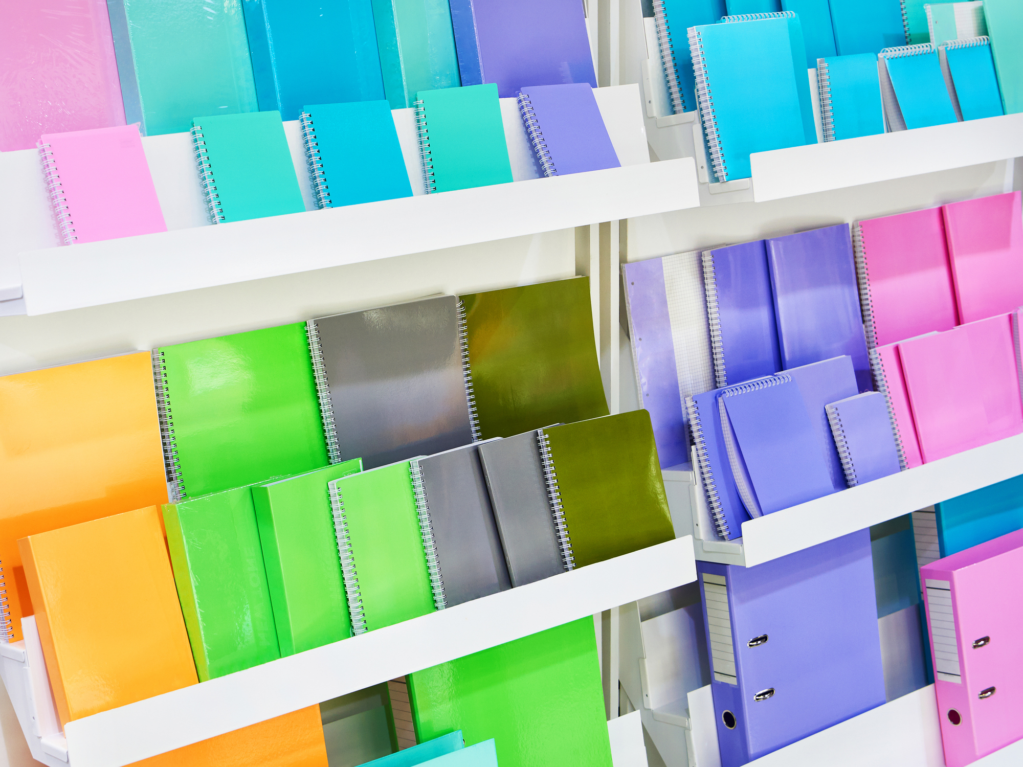 Numerous colorful notebooks and journals on shelves in a store, organized and clean