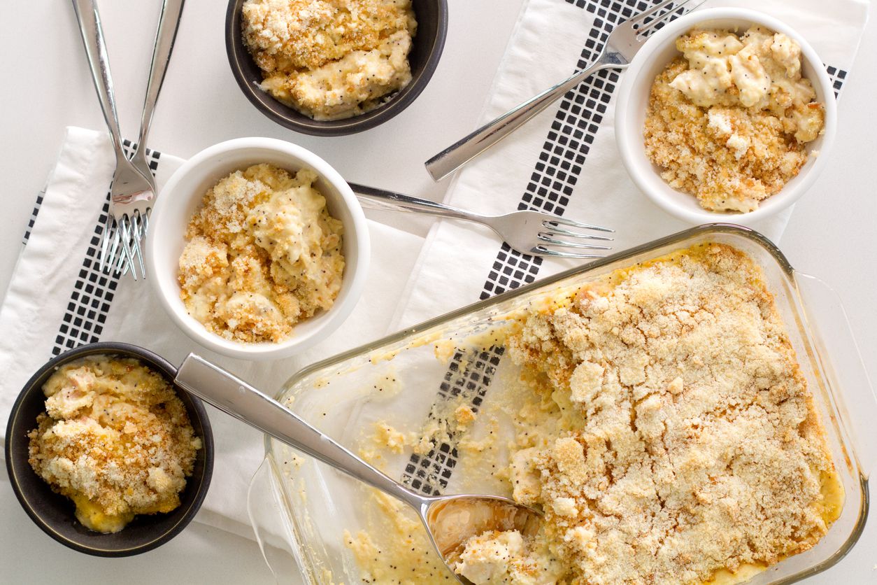 Poppy seed chicken casserole in glass baking dish with some of it served in small ramekins
