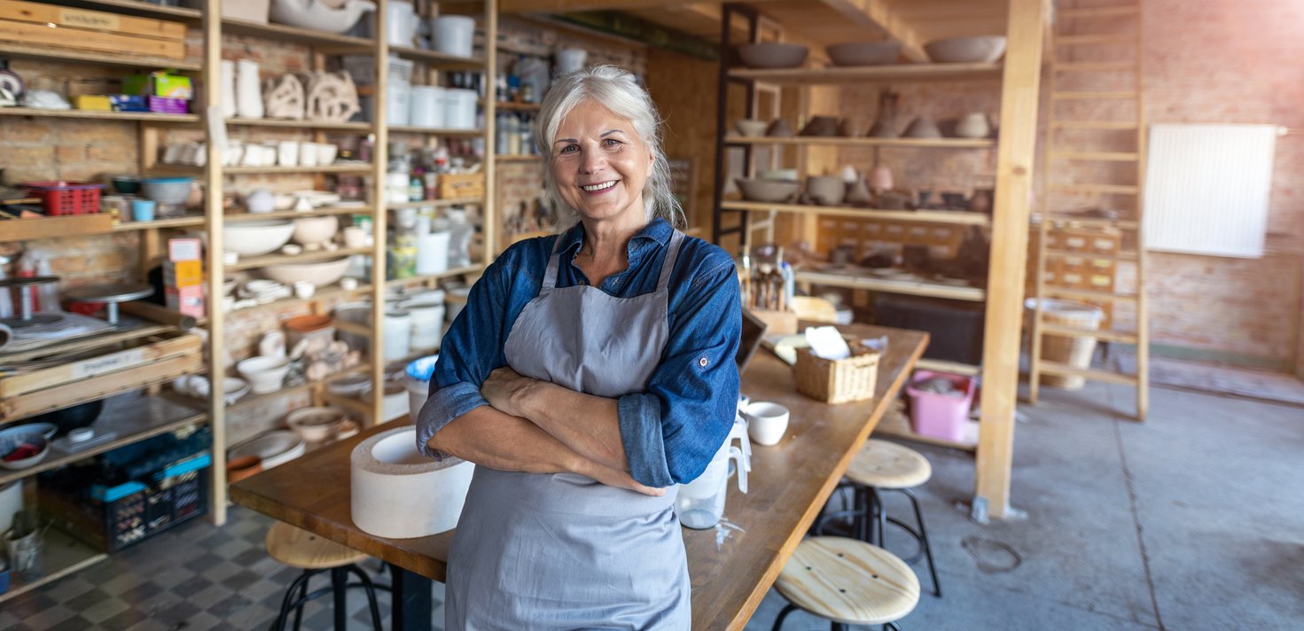 Portrait of senior female pottery artist in her art studio showing one of many side hustles that make money.