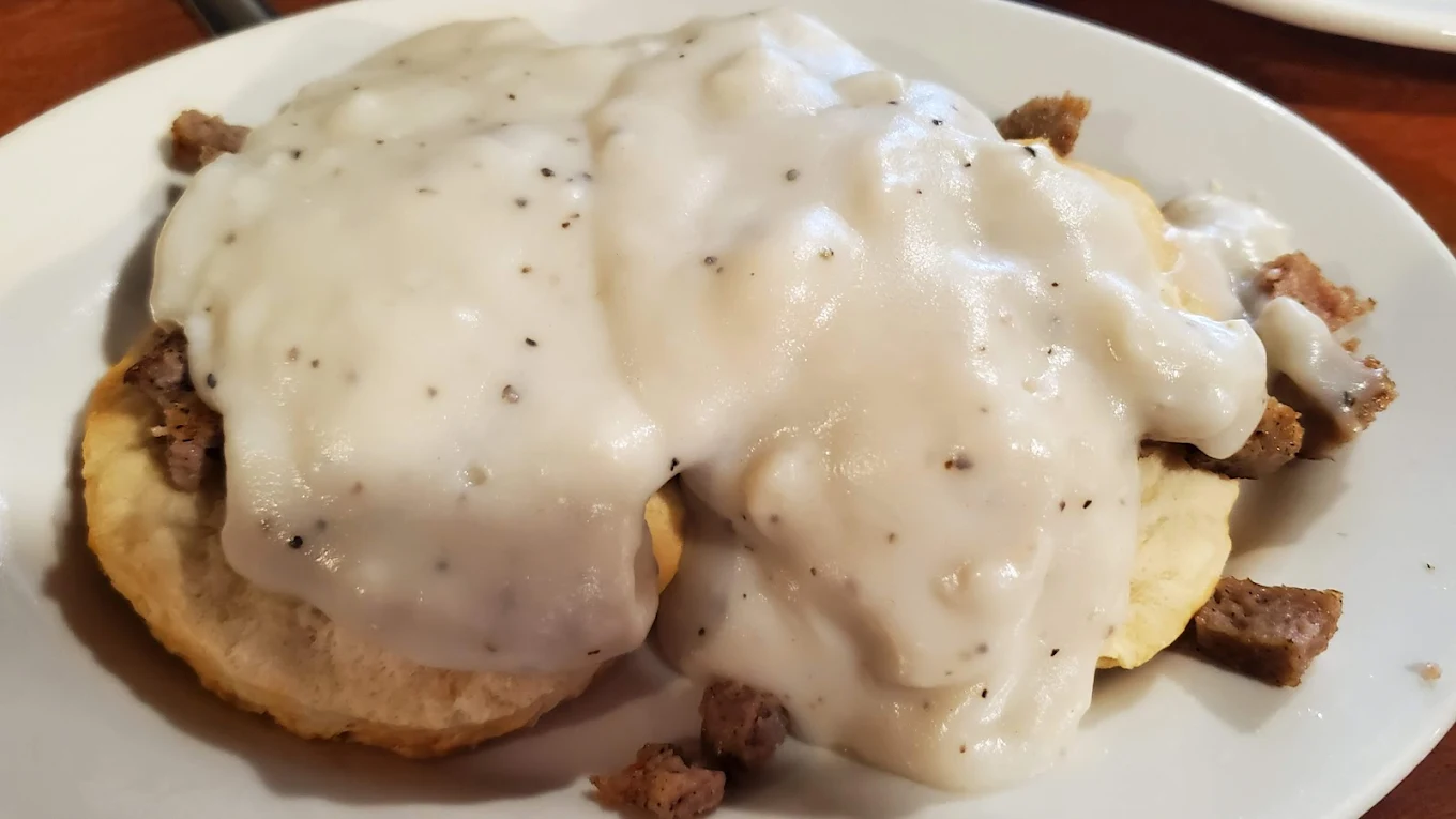 Two biscuit halves topped with sausage gravy and sausage pieces, served on a white plate—no wonder it’s considered one of the best breakfast foods in every state.