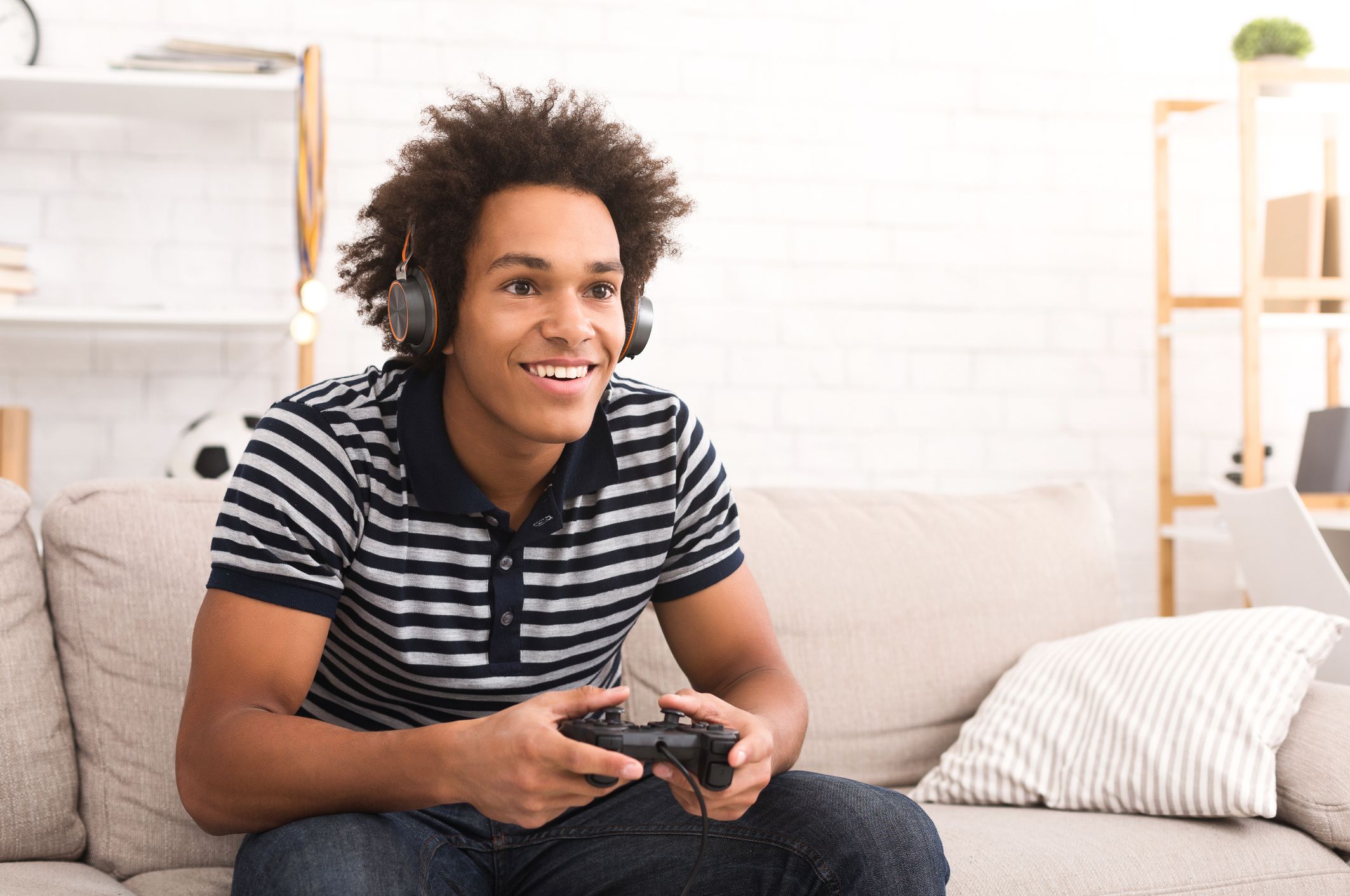 African-american teenager playing video games on console at home, copy space