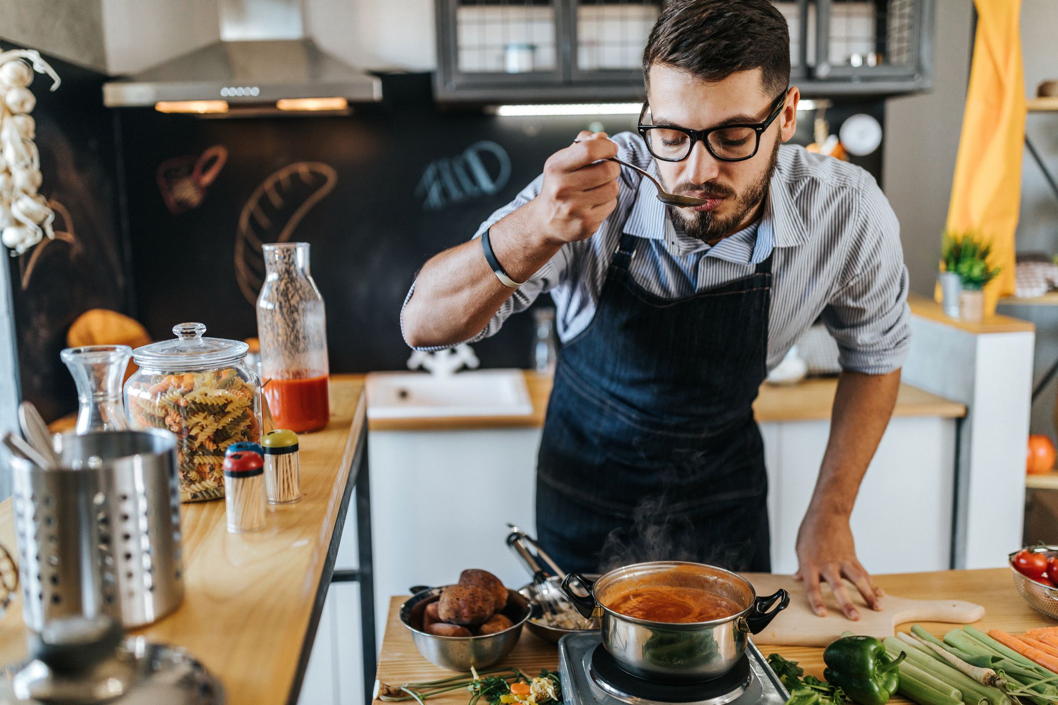 Photo of chef tasting delicious lunch he is preparing in the kitchen