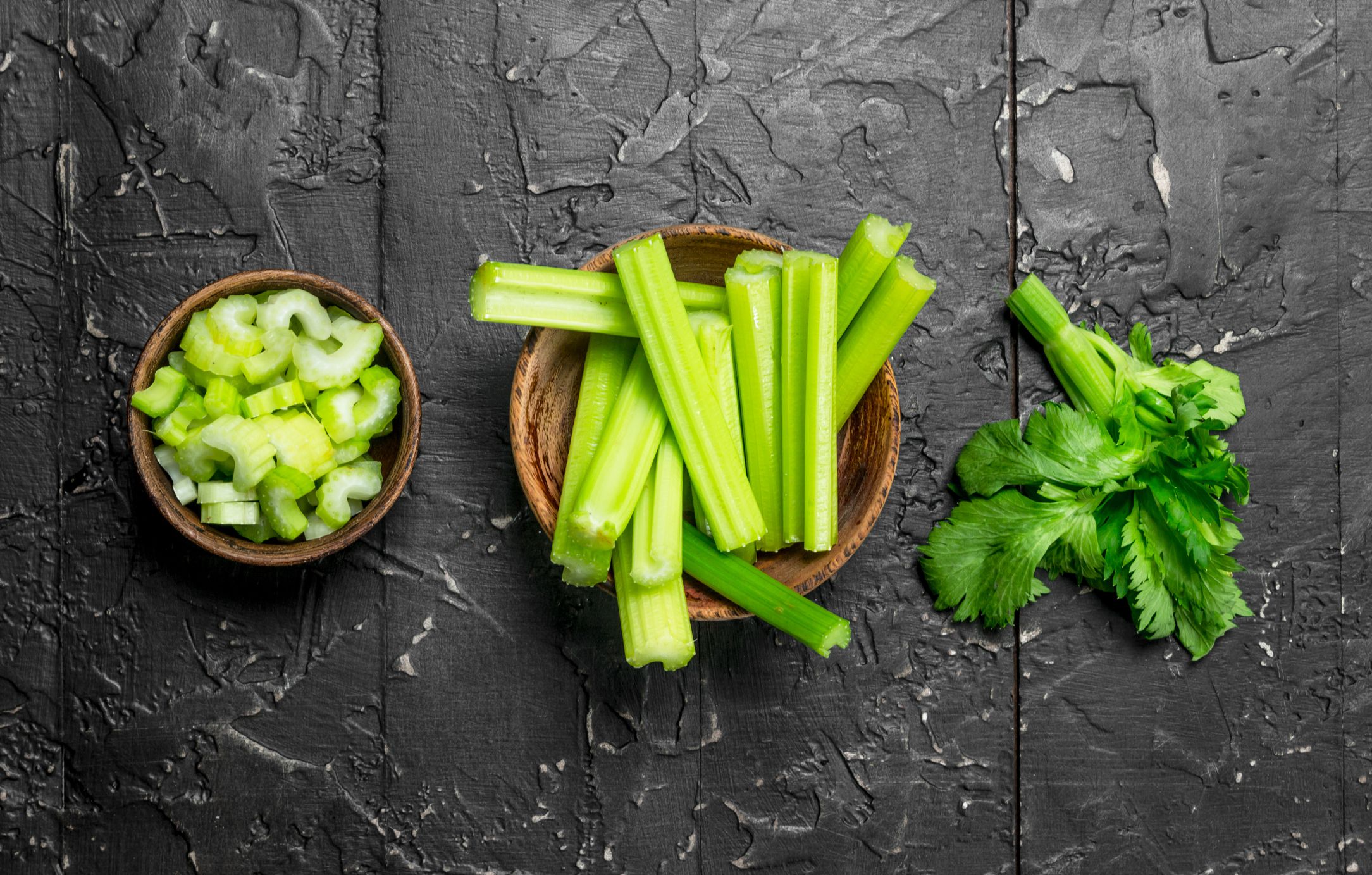 Pieces of celery in a wooden bowl. On rustic background