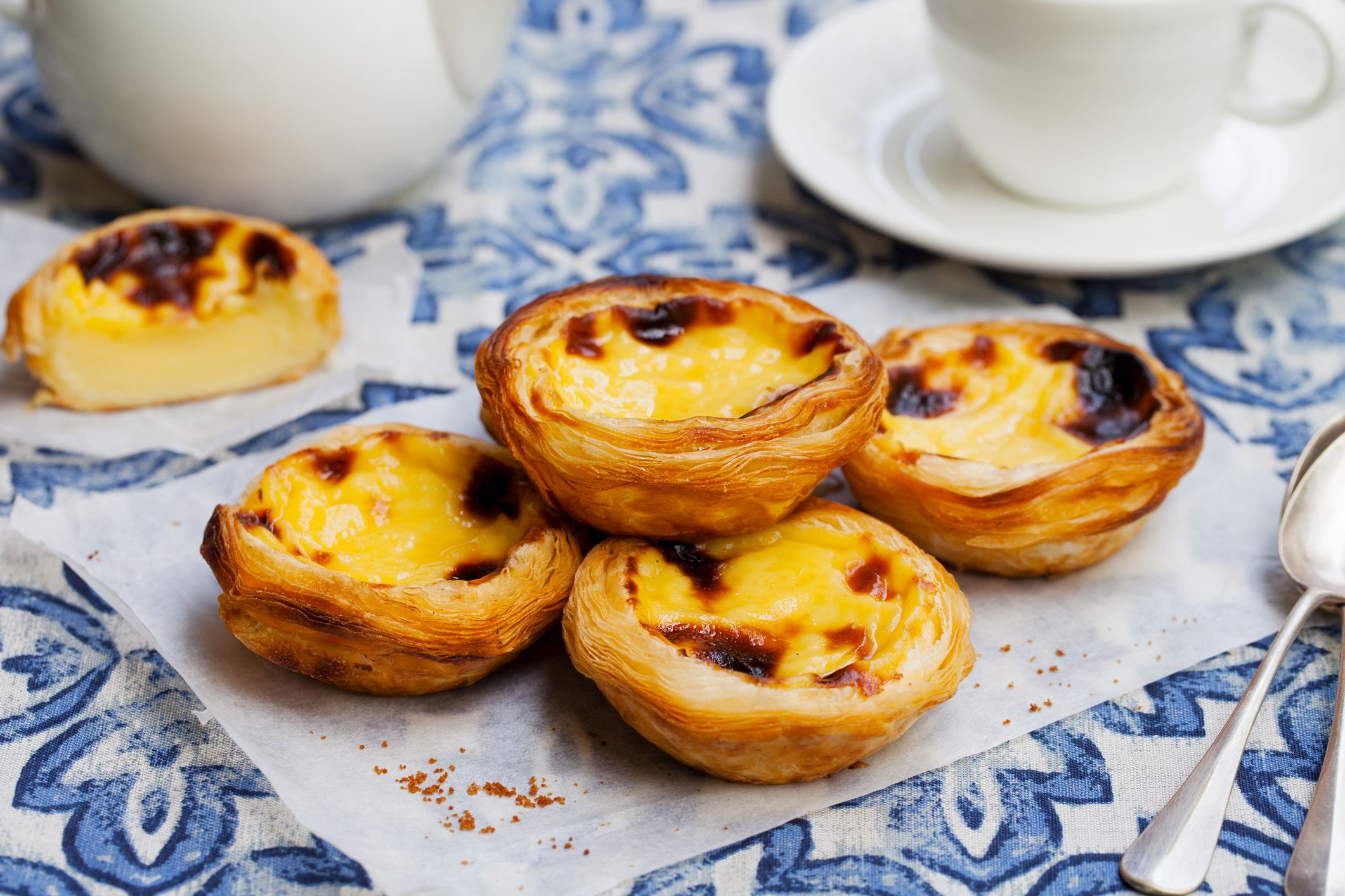 Egg tart, traditional Portuguese dessert, pastel de nata on a parchment paper. Blue background