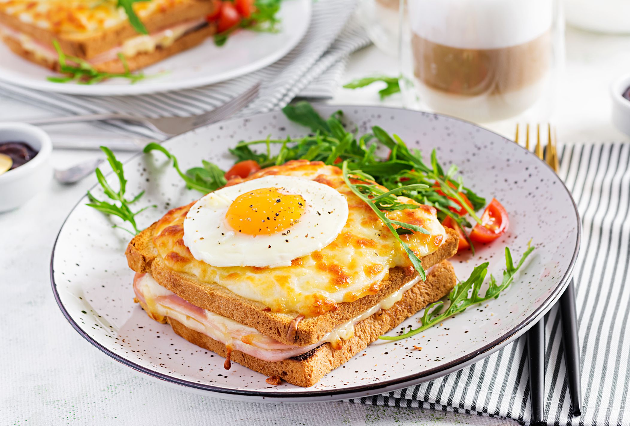 Breakfast. Hot sandwich. Croque madame sandwich and a cup of latte macchiato coffee on the table. French cuisine. Copy space