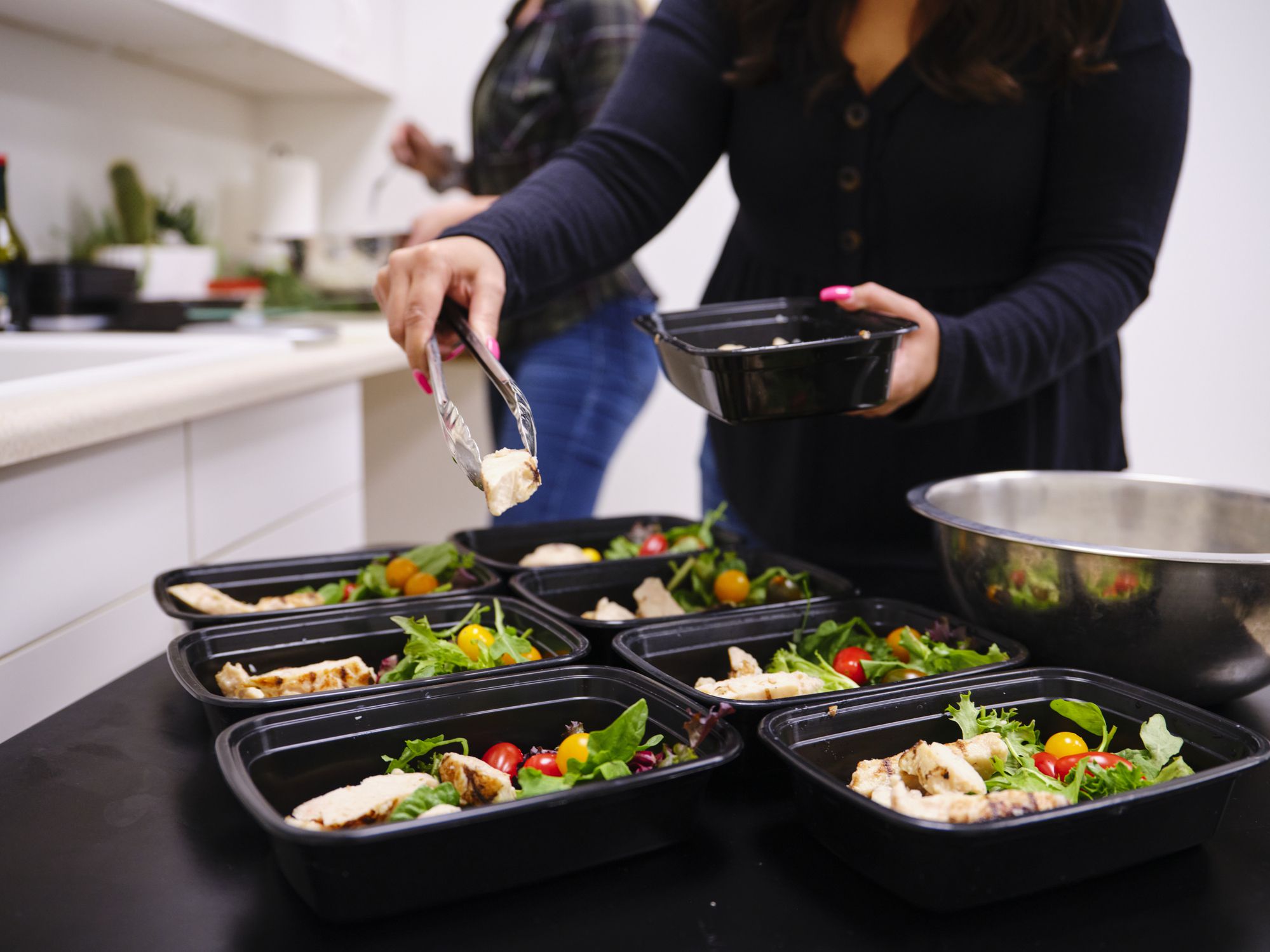 A woman prepares a healthy meal in her kitchen, using a scale to portion the ingredients.