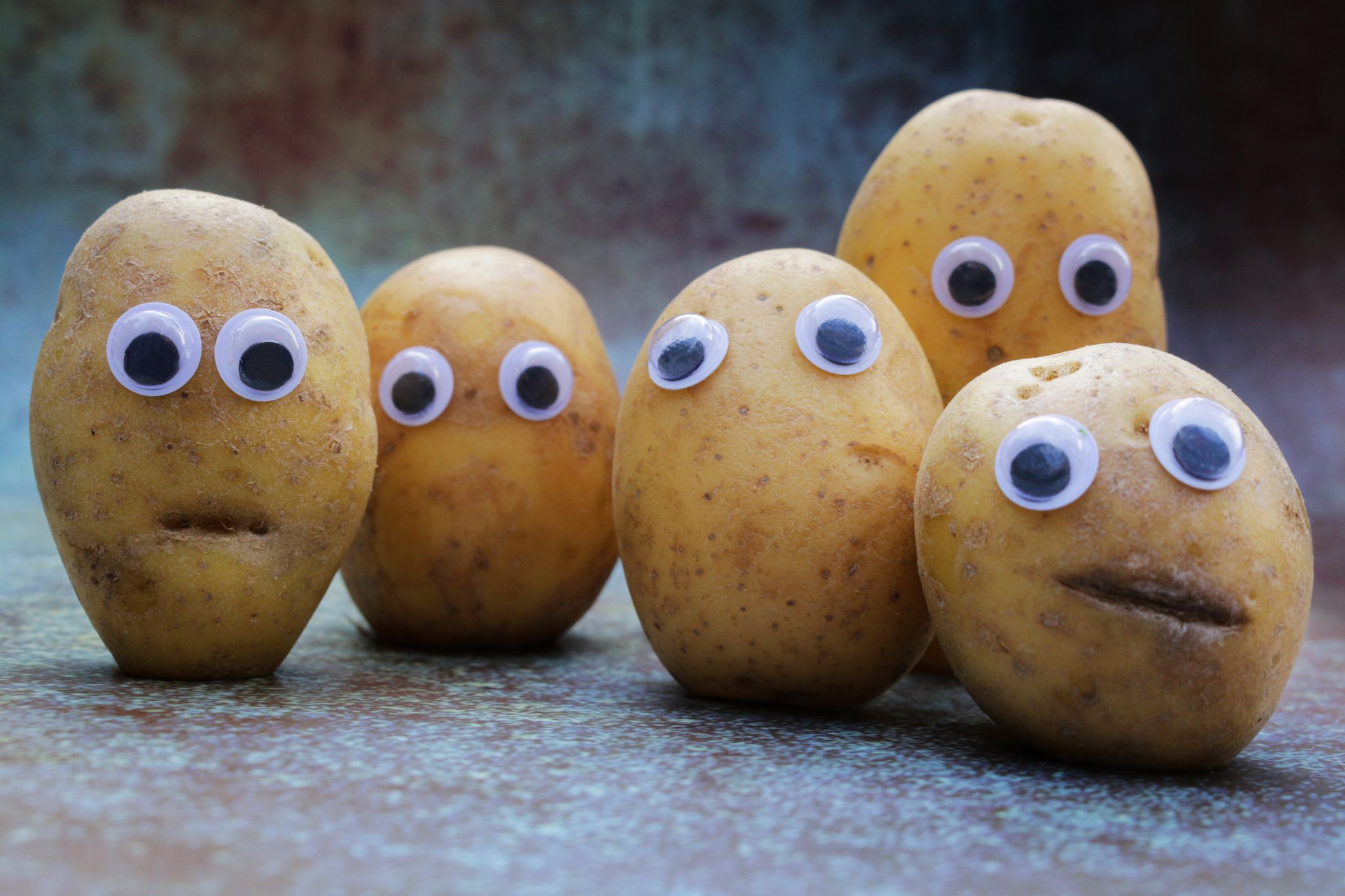 Five potatoes of varying sizes and shapes with googly eyes on them.